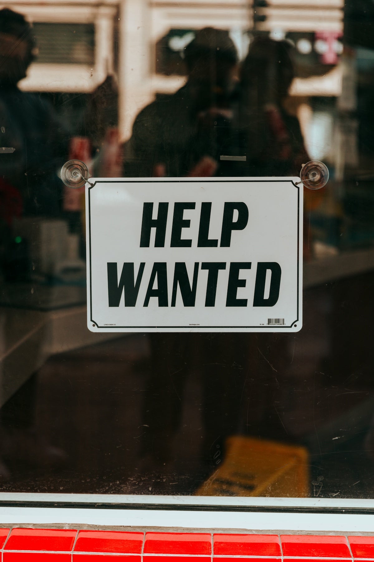 a sign that says help wanted in front of a window
