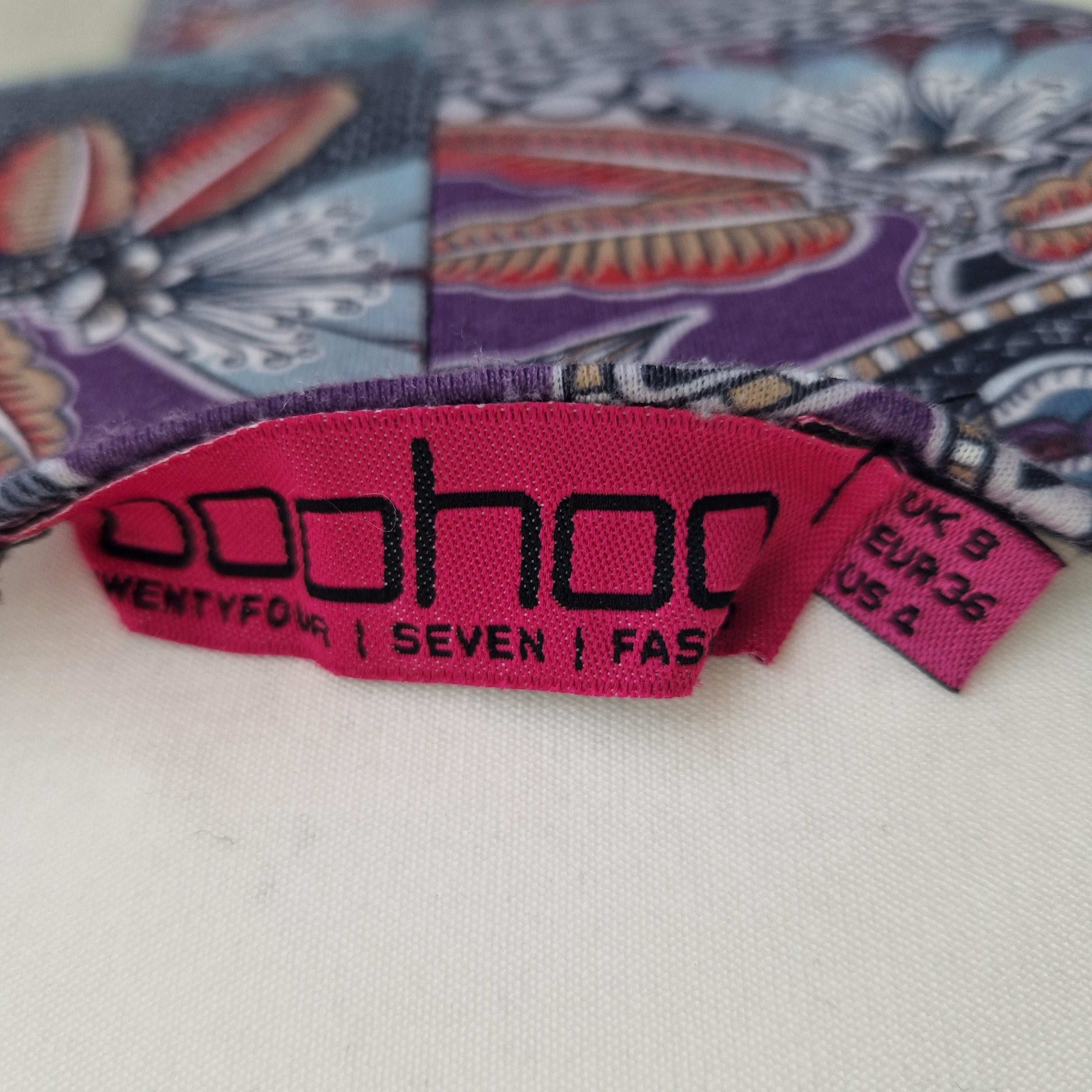 A close-up of a Boohoo brand label on a patterned, multicoloured sleeveless beach top.