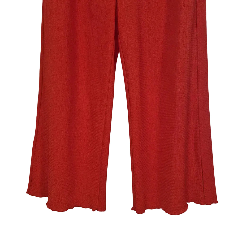 A pair of red wide-leg trousers with a textured fabric and scalloped hems.