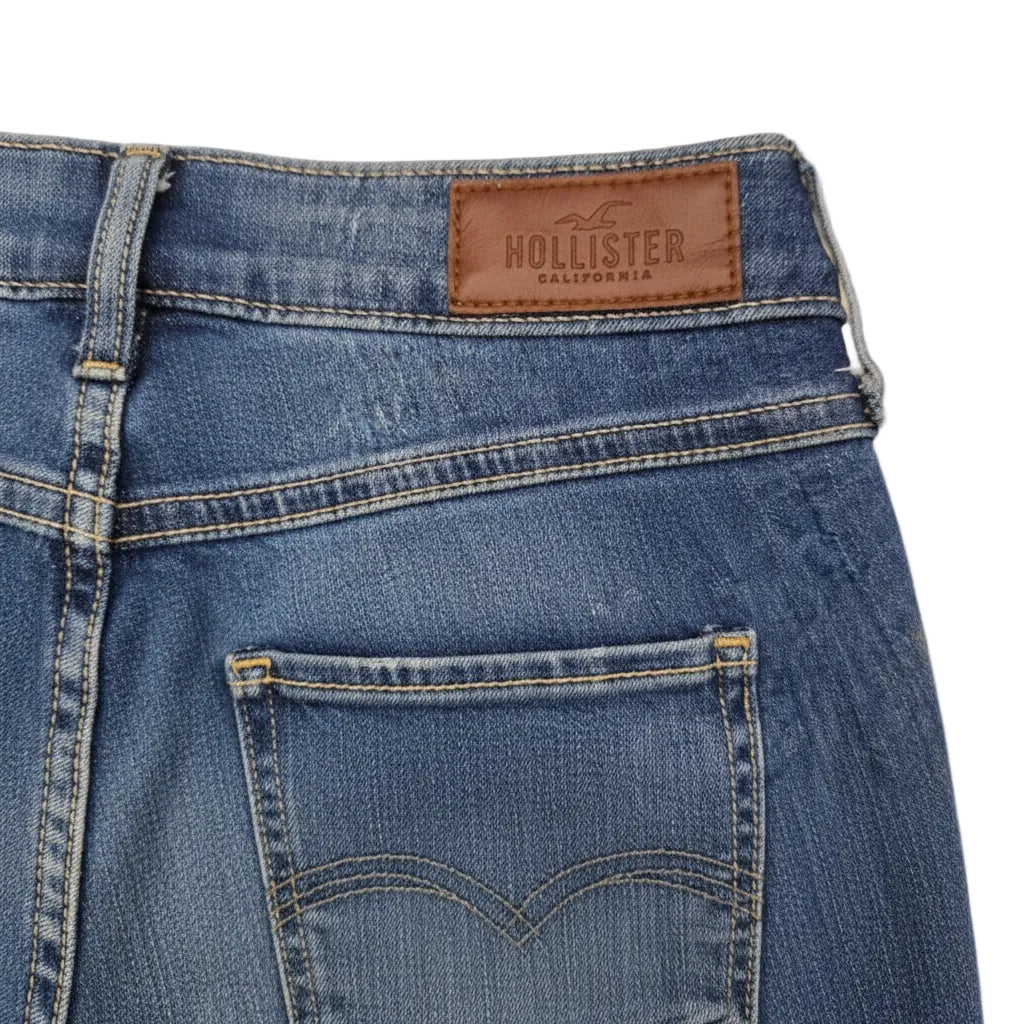 A close-up of the back of medium blue Hollister denim jeans featuring a brown leather brand patch.