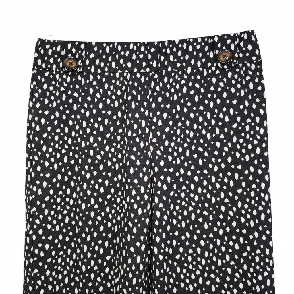 Black tapered trousers with a white speckled pattern and decorative buttons at the waist.