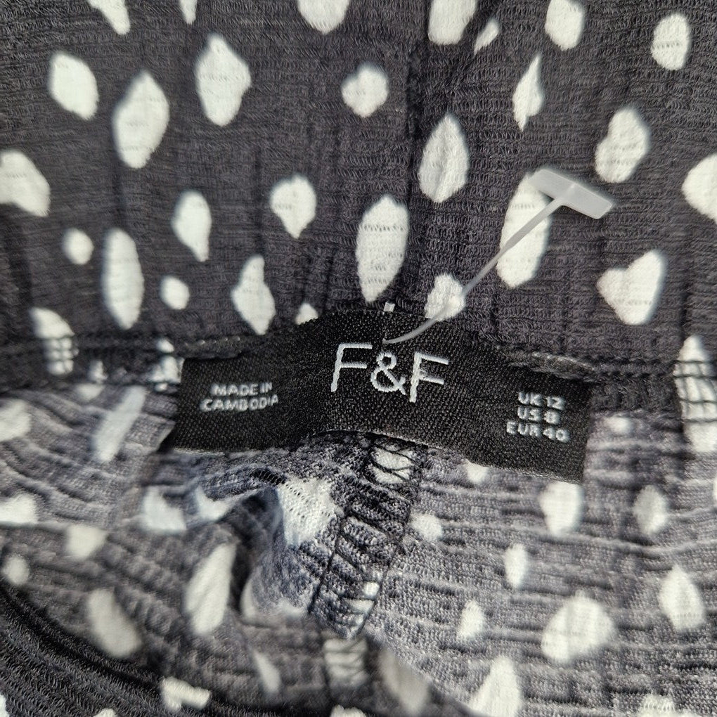 A close-up of the F&F brand label on black and white patterned crepe trousers.