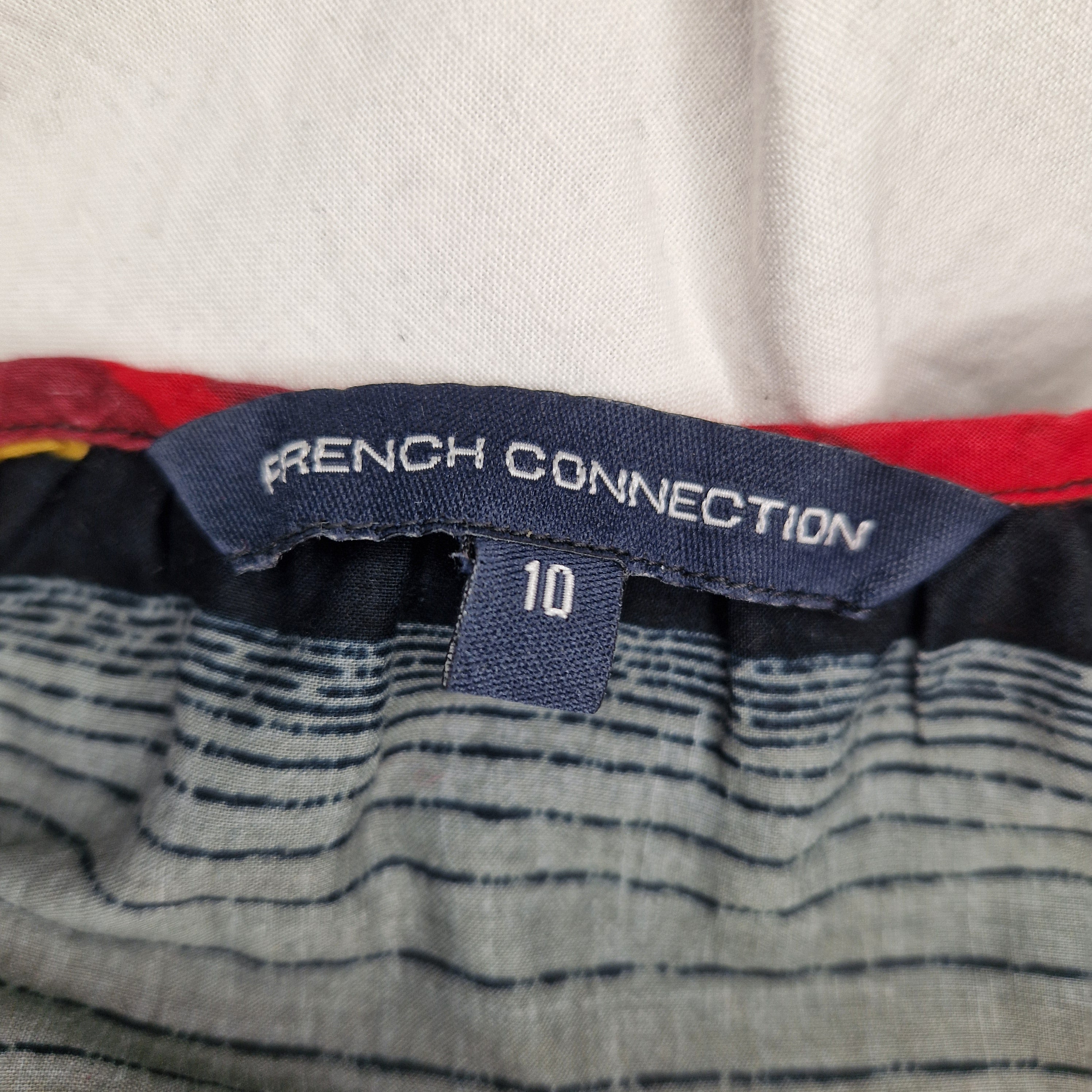 A close-up of a French Connection brand label on a multicolour striped cami top, size UK 10.