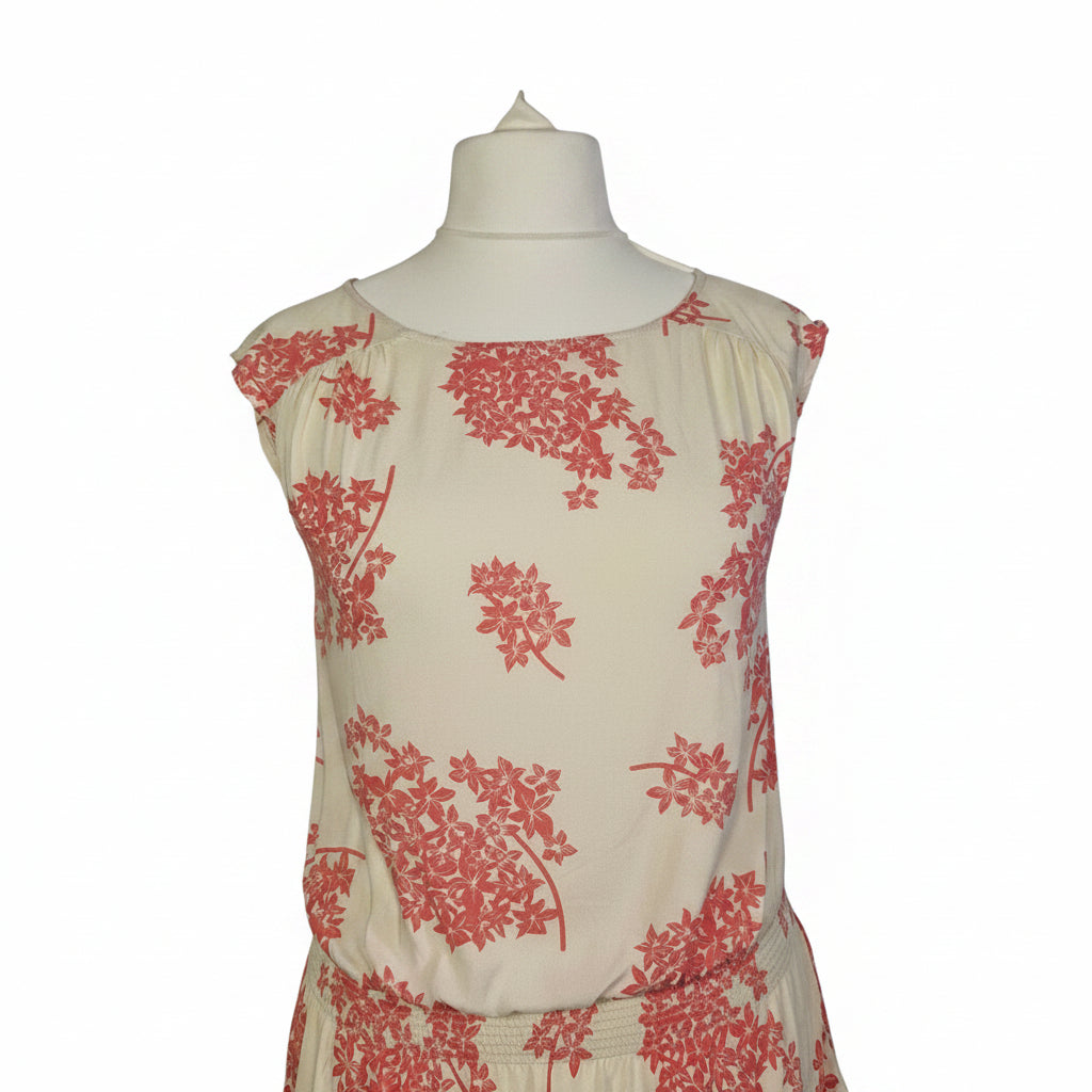 A sleeveless cream blouse by F&F featuring a pink floral print and a smocked hem.