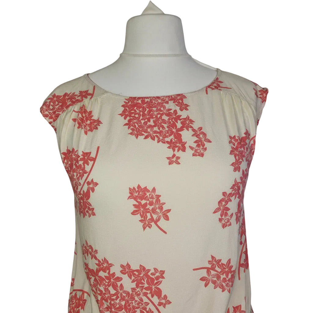 A sleeveless cream blouse by F&F featuring a pink floral print and a smocked hem.