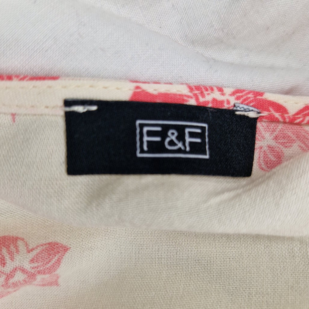A close-up of an F&F brand label on a cream blouse with a pink floral print.