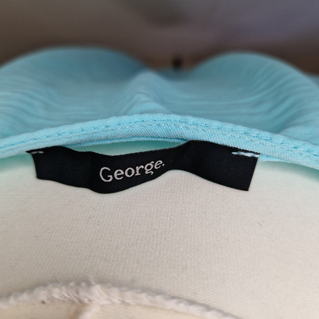 A close-up view of the black George brand label inside a light blue V-neck blouse.