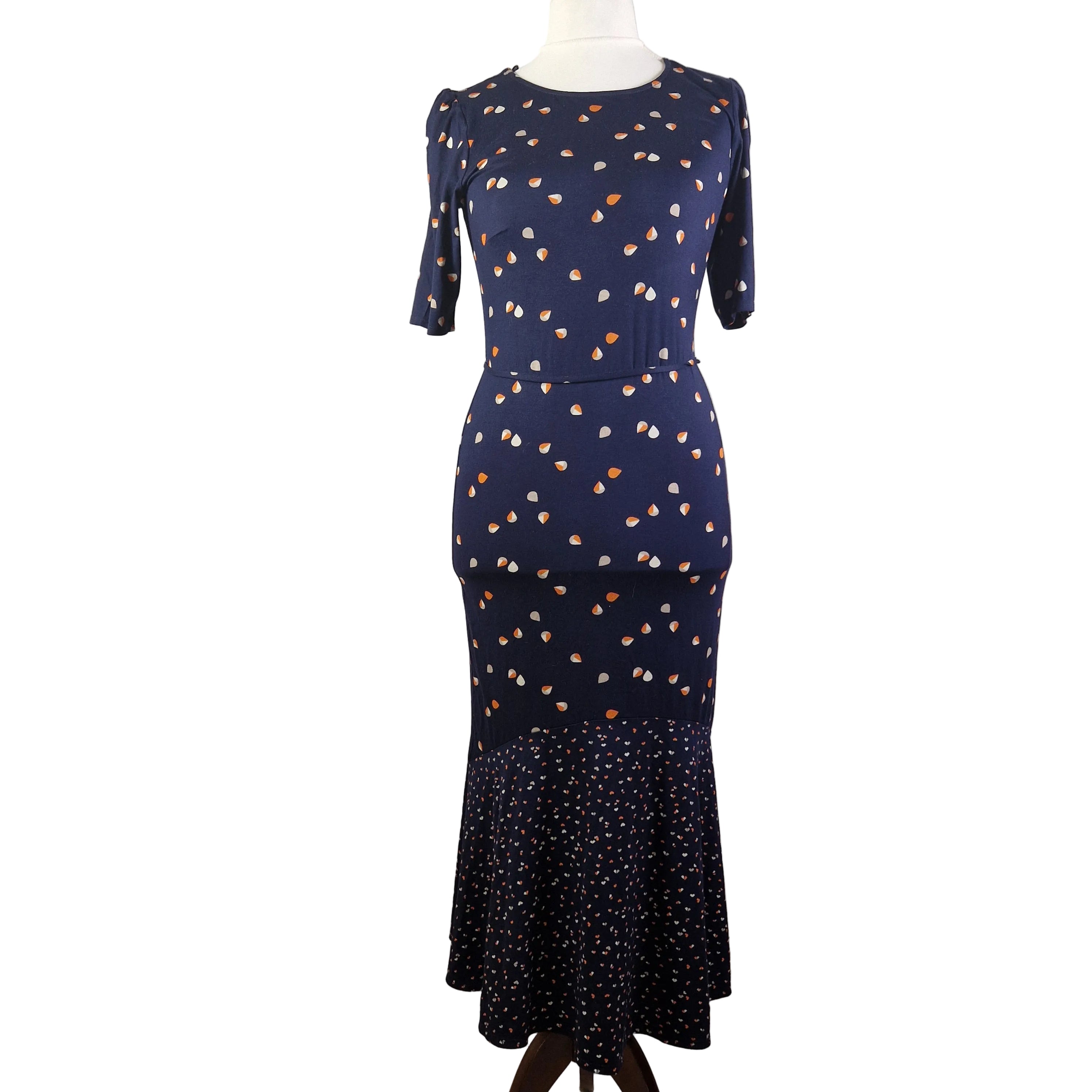 A navy blue fit and flare dress with a teardrop print and a ruffled hem on a mannequin.