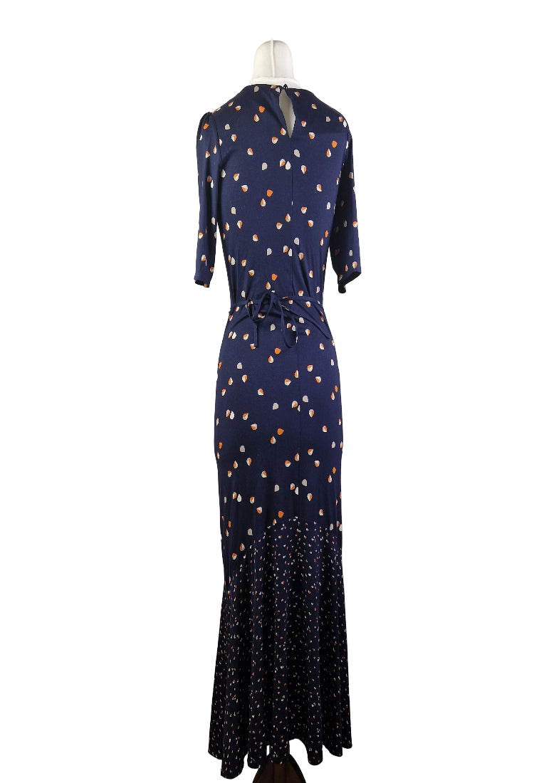 A navy blue fit and flare dress with a teardrop print and a ruffled hem on a mannequin.