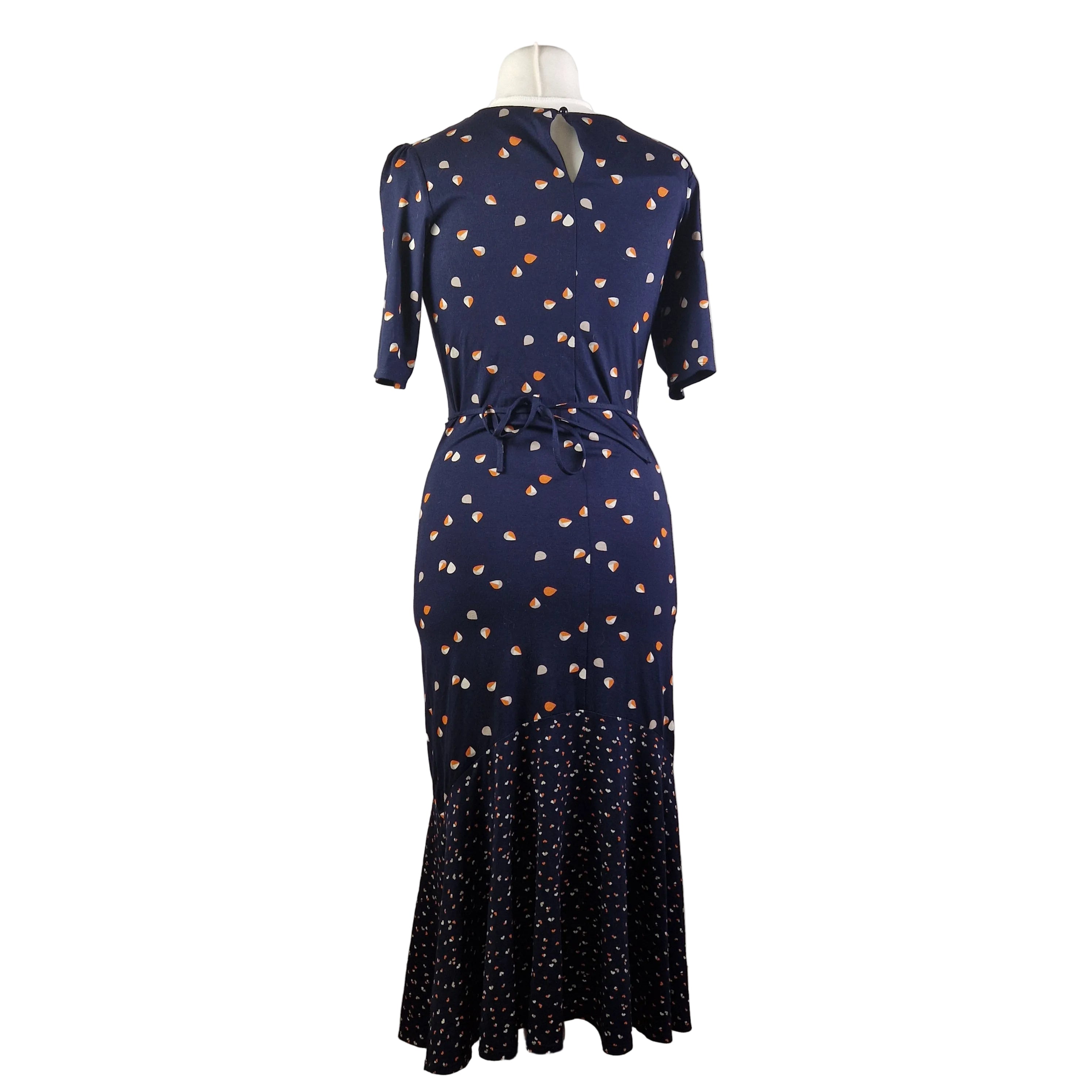 A navy blue fit and flare dress with a teardrop print and a ruffled hem on a mannequin.