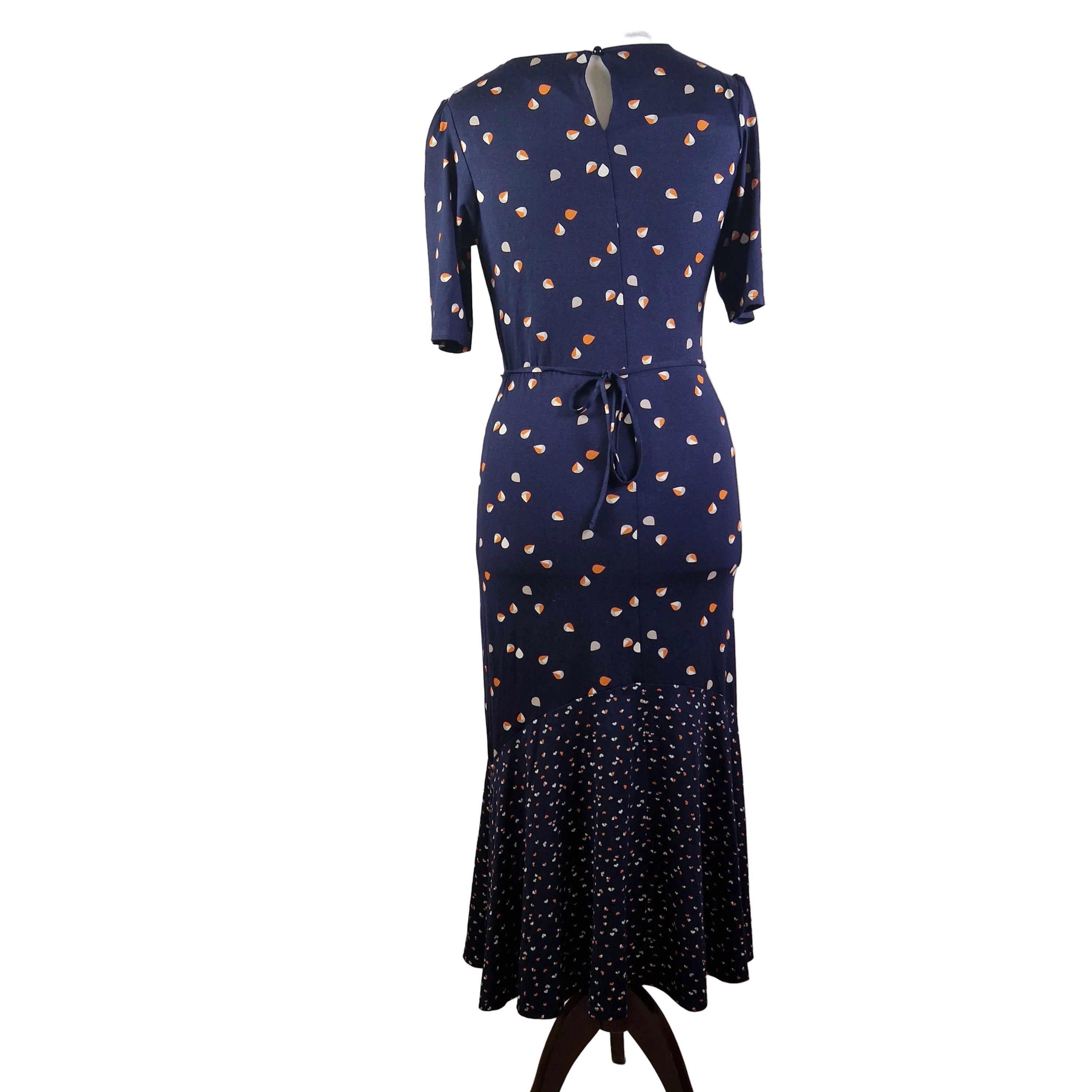 A navy blue fit and flare dress with a teardrop print and a ruffled hem on a mannequin.