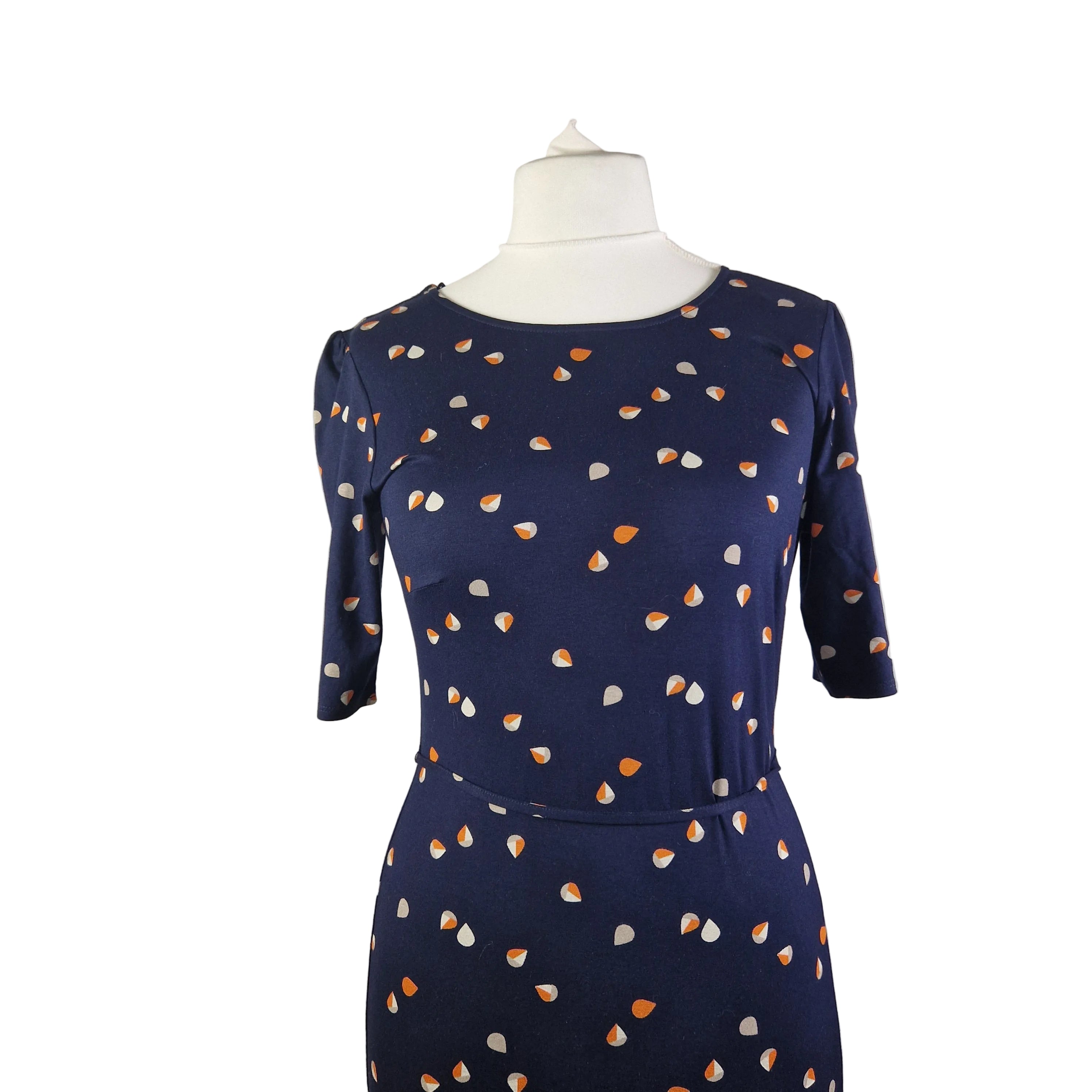 A navy blue fit and flare dress featuring a white and orange teardrop print and short sleeves.