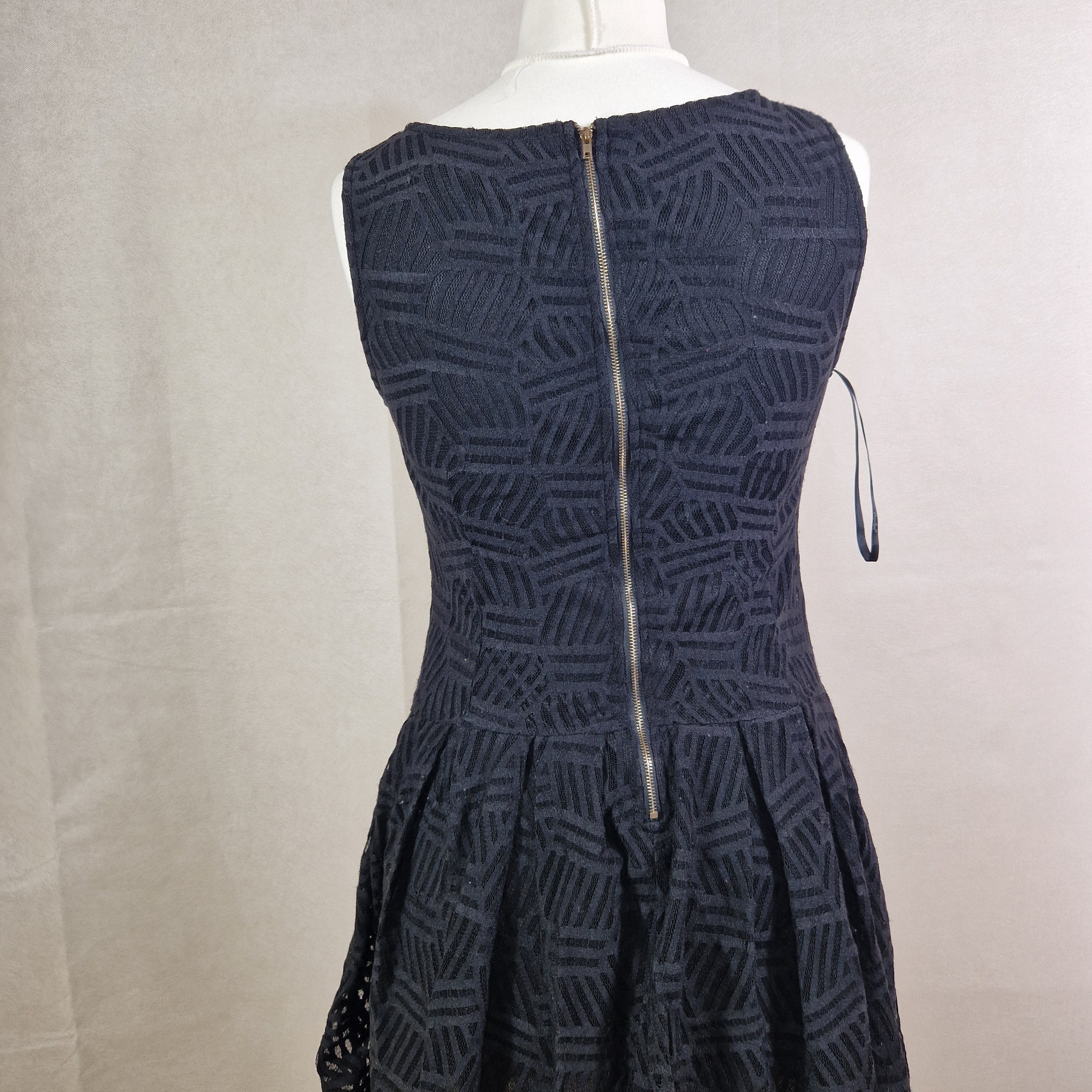 Black textured dress on a mannequin against a neutral background