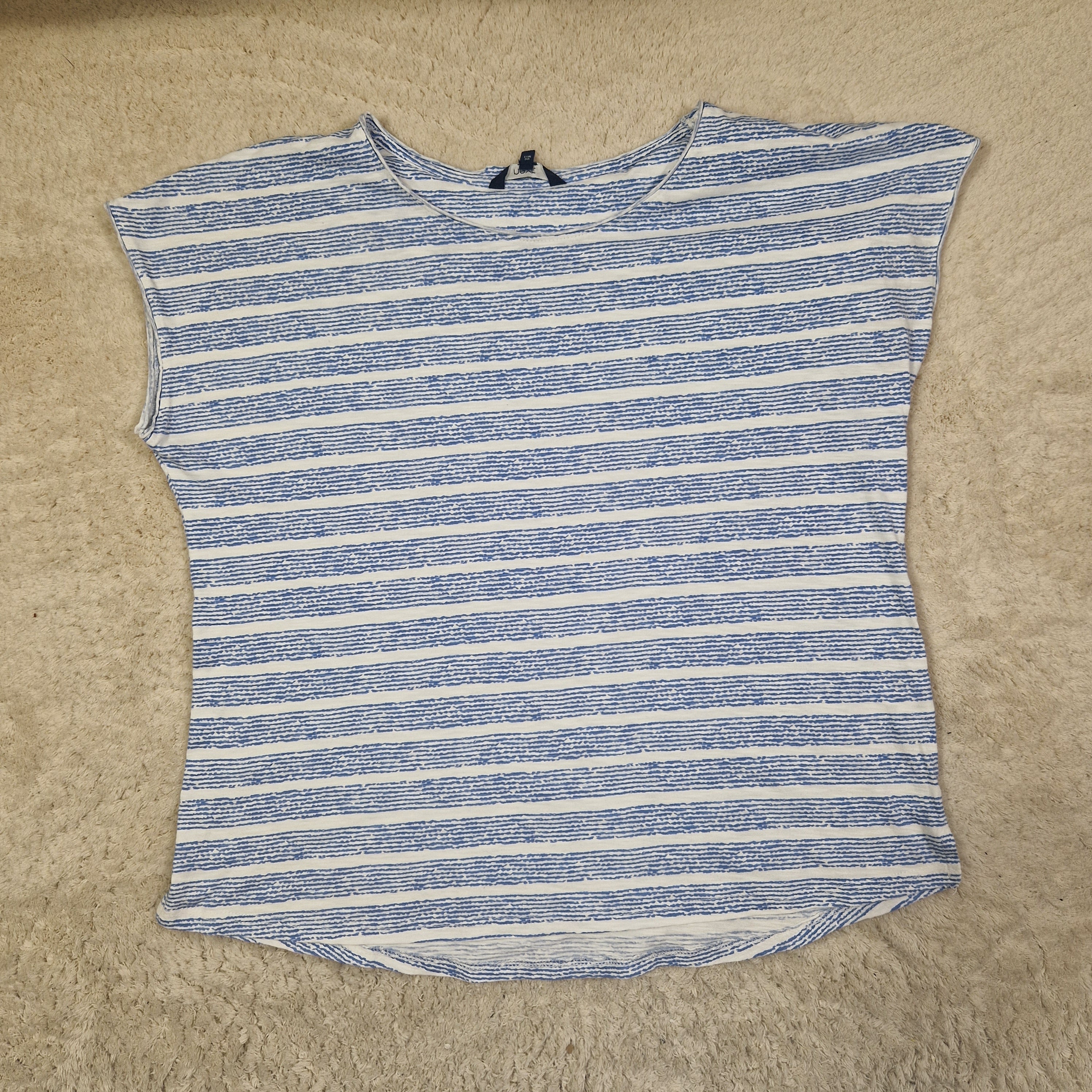 Blue and white striped sleeveless top on a beige carpet