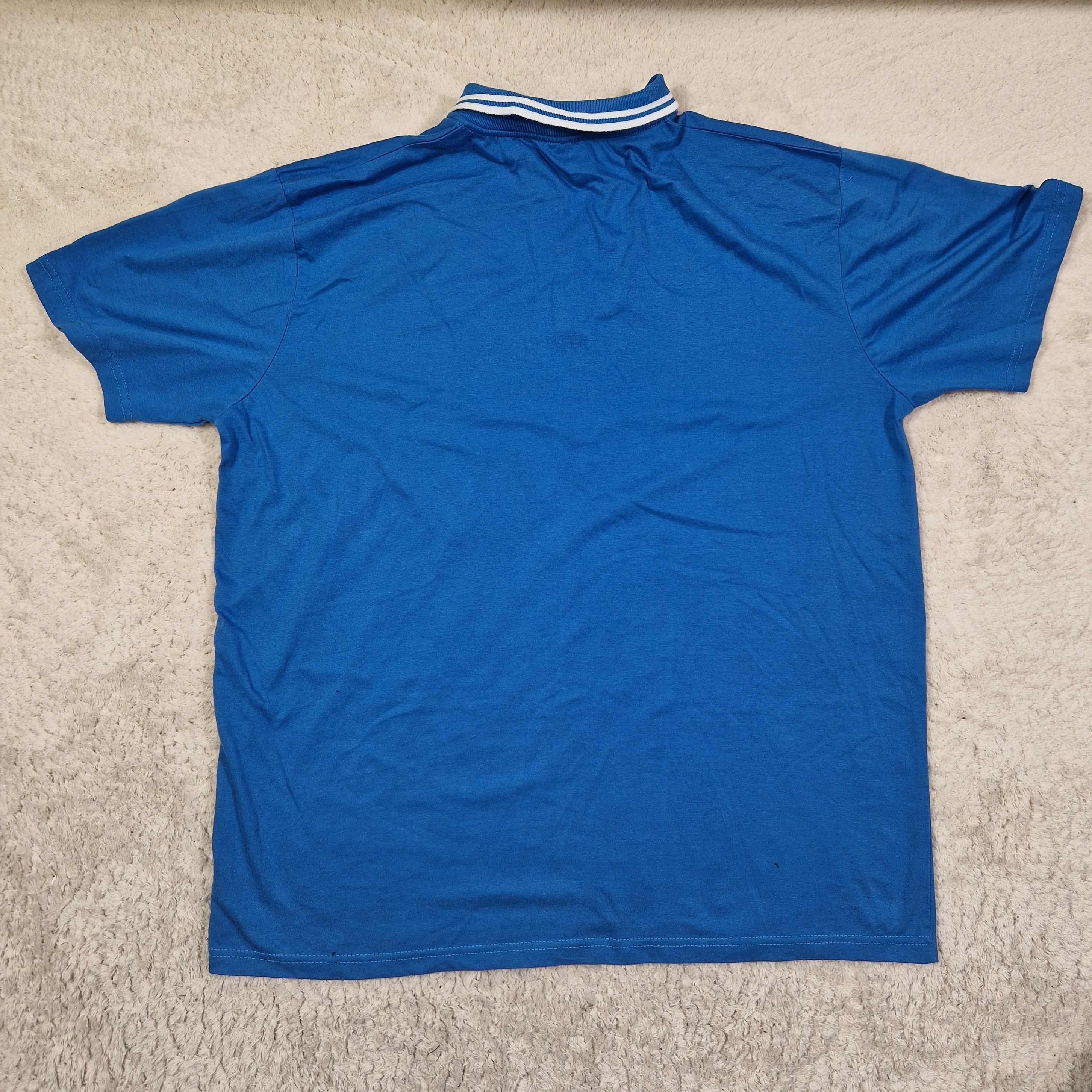 Blue t-shirt with white stripes on sleeves on a beige carpet
