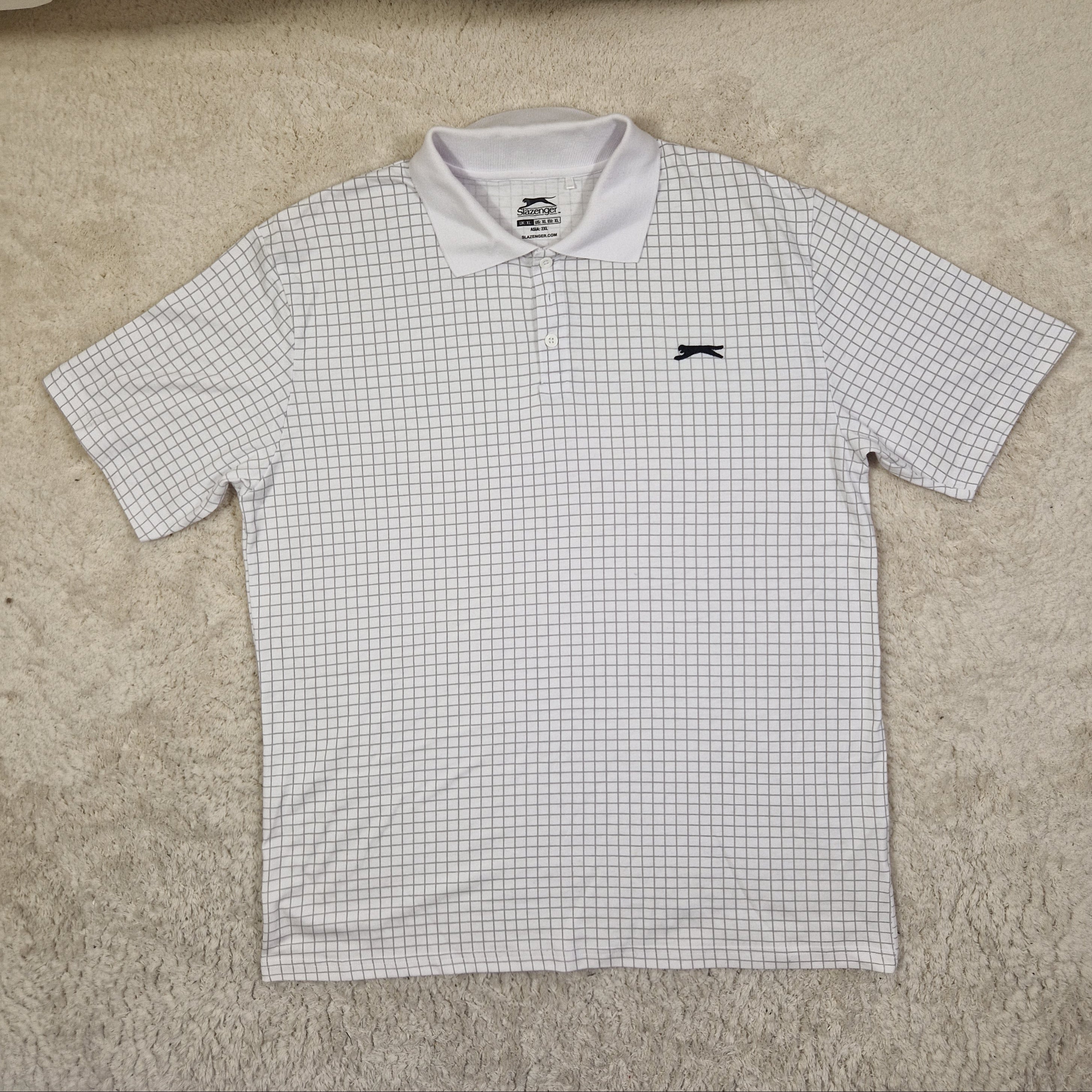 White checkered shirt with a logo on a beige surface