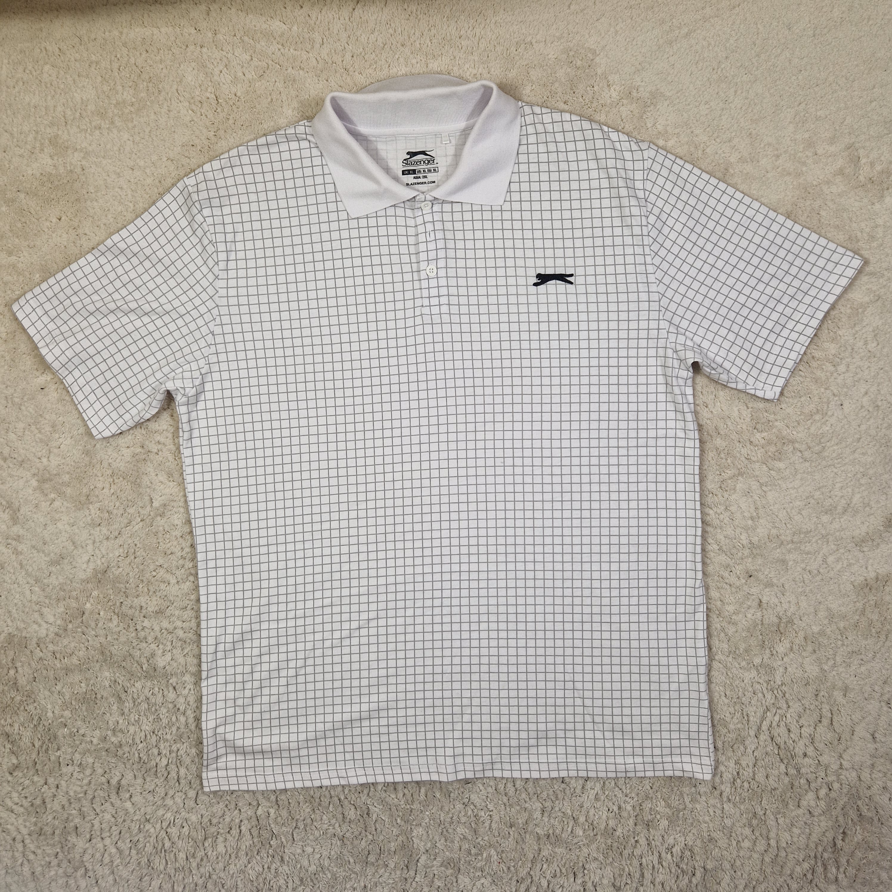 White checkered shirt with black logo on a beige surface