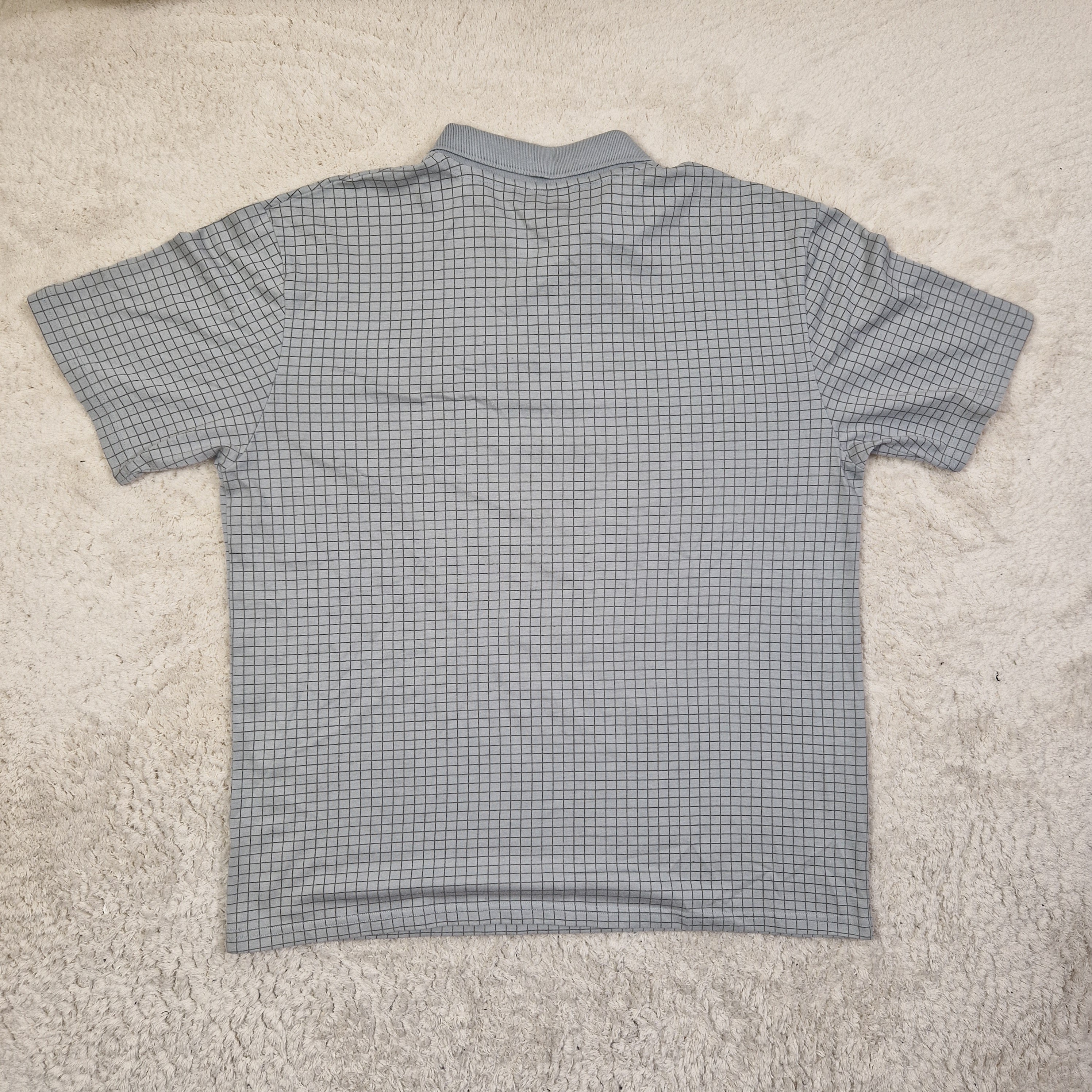Gray checkered sleeveless shirt on a beige carpet