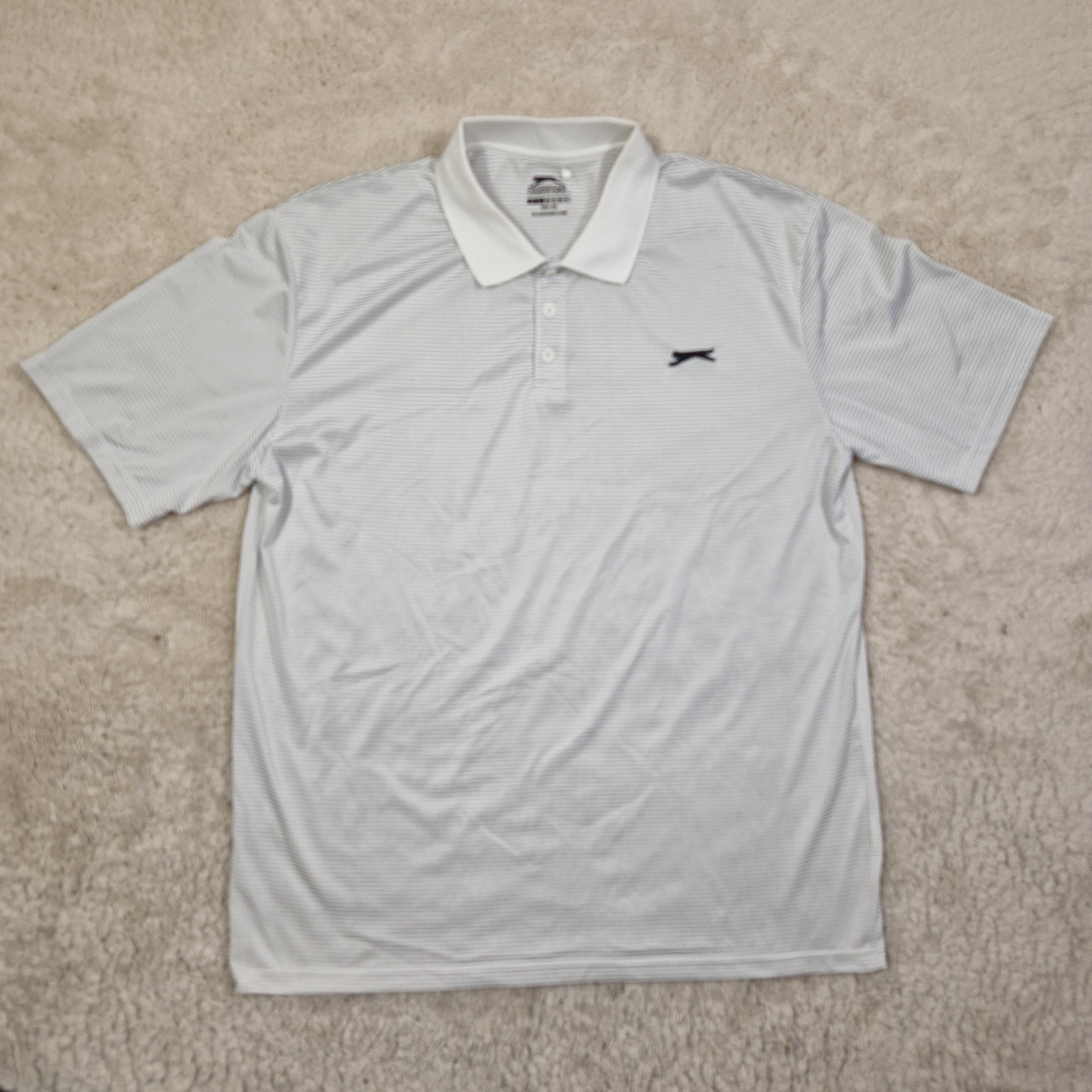 Light gray t-shirt with a small logo on a beige carpet
