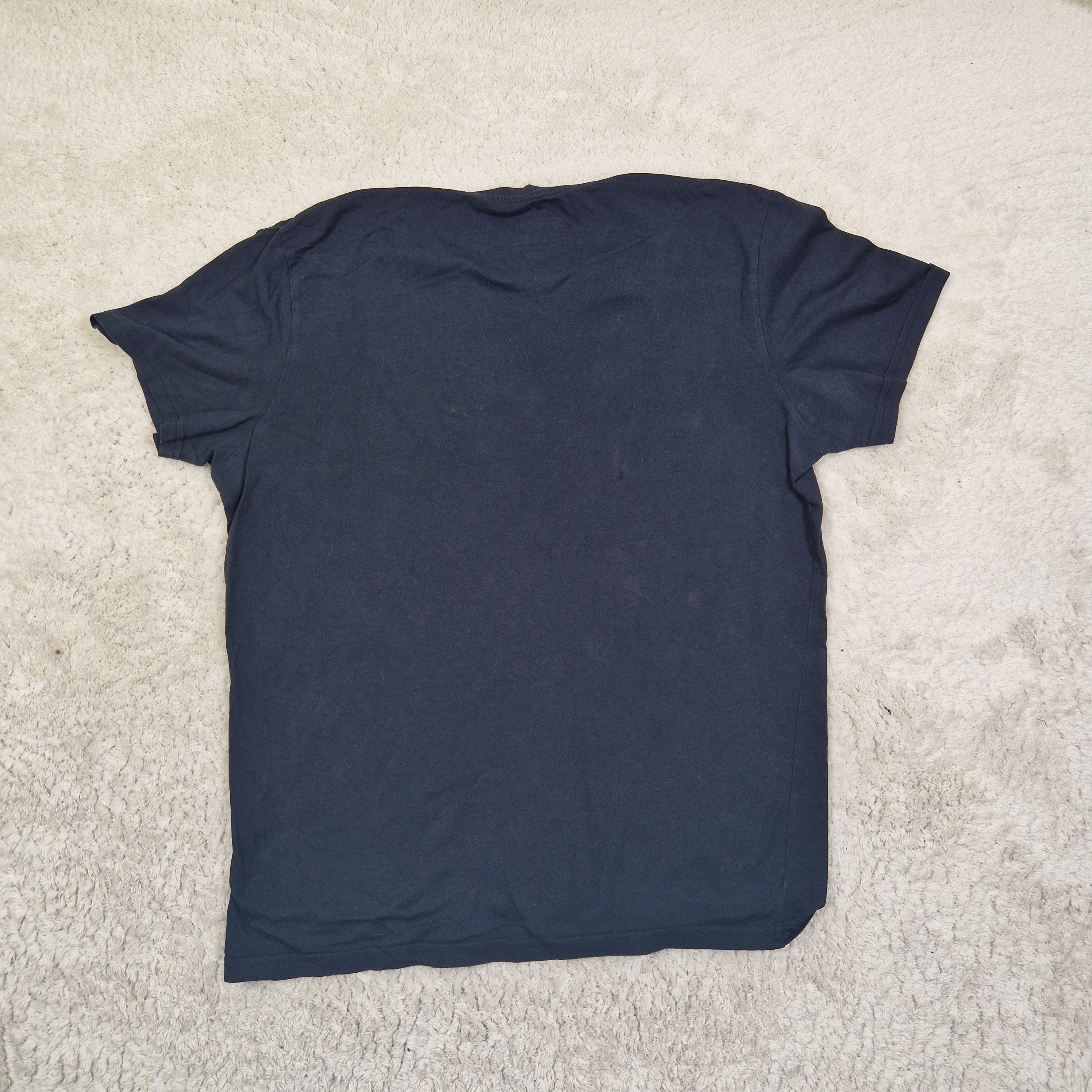Folded navy blue t-shirt on a beige carpet