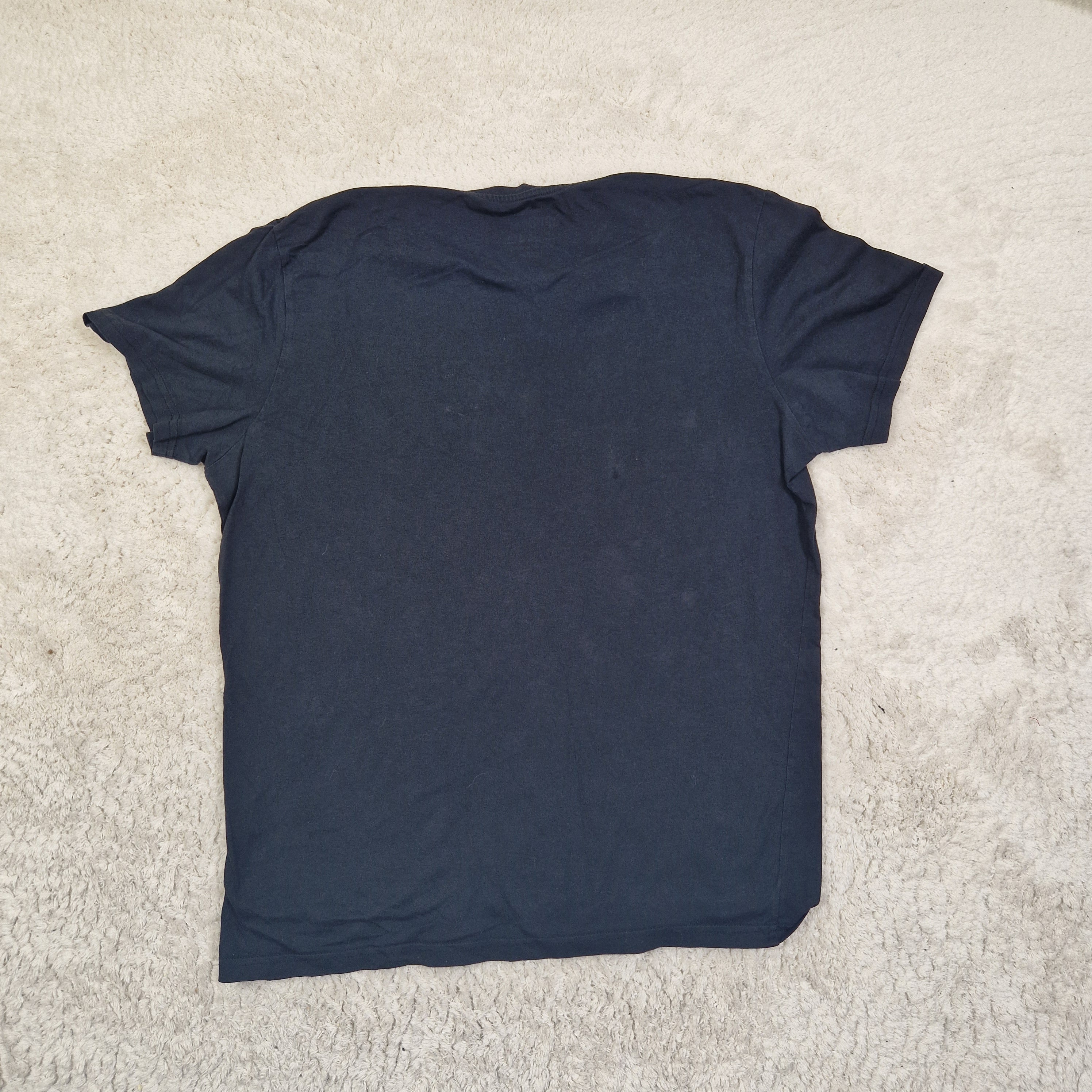 Folded navy blue t-shirt on a beige carpet