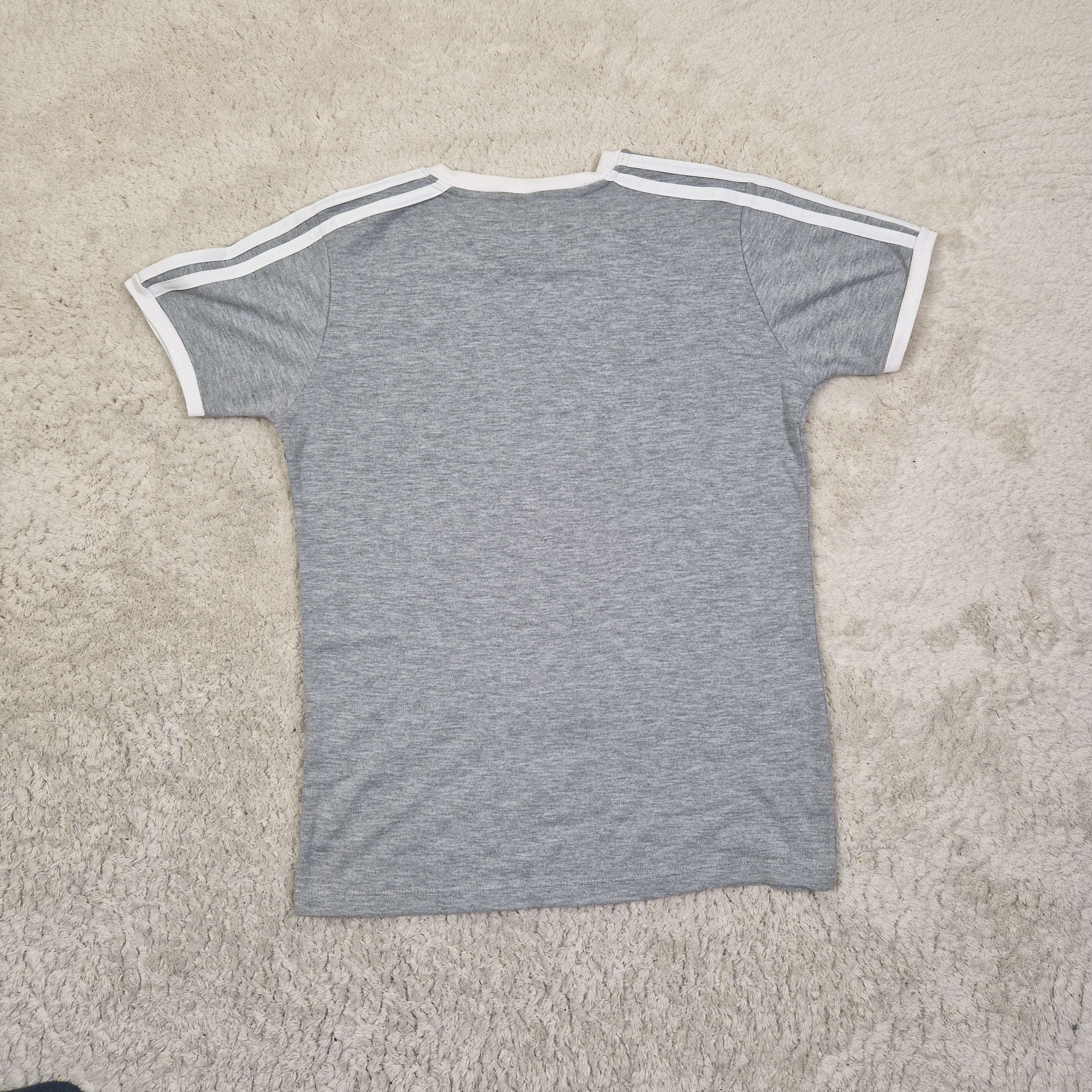 Gray t-shirt with white trim on a beige carpet