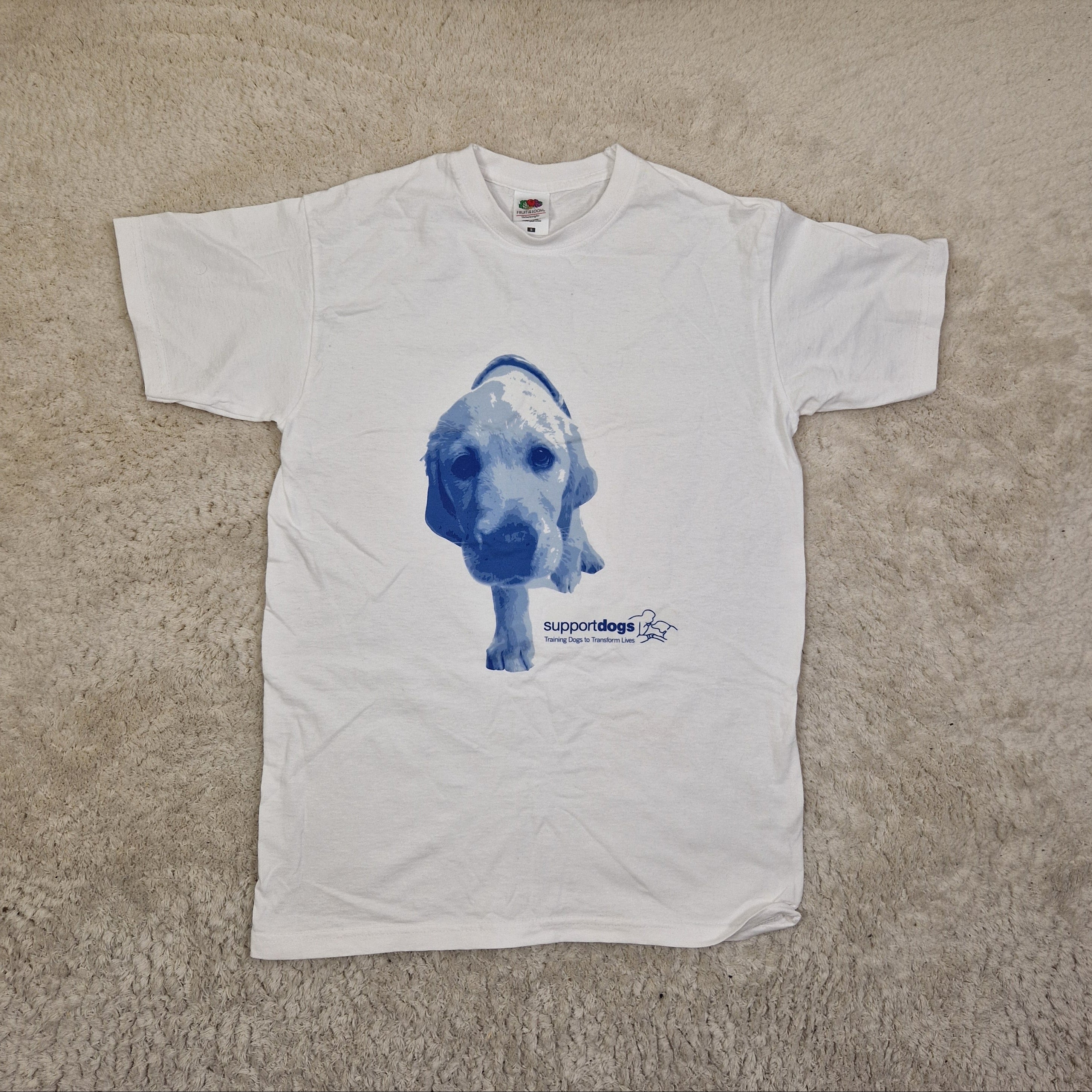 White t-shirt with blue graphic of a dog on a beige carpet