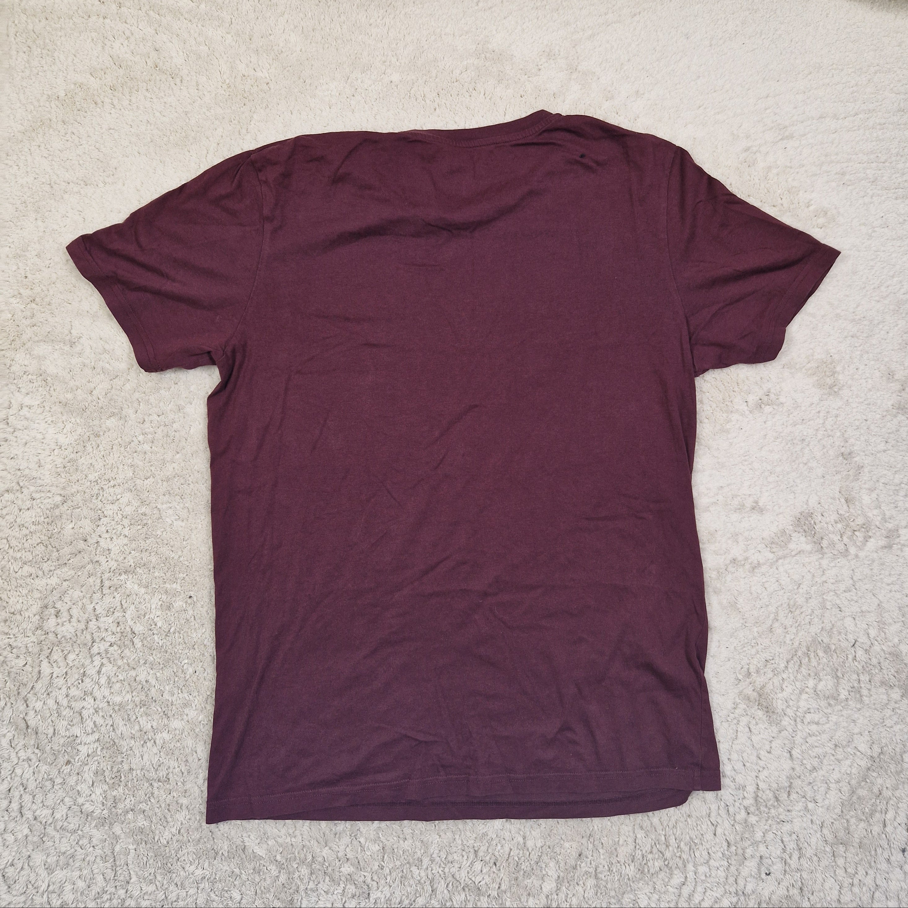 Maroon t-shirt on a beige carpet