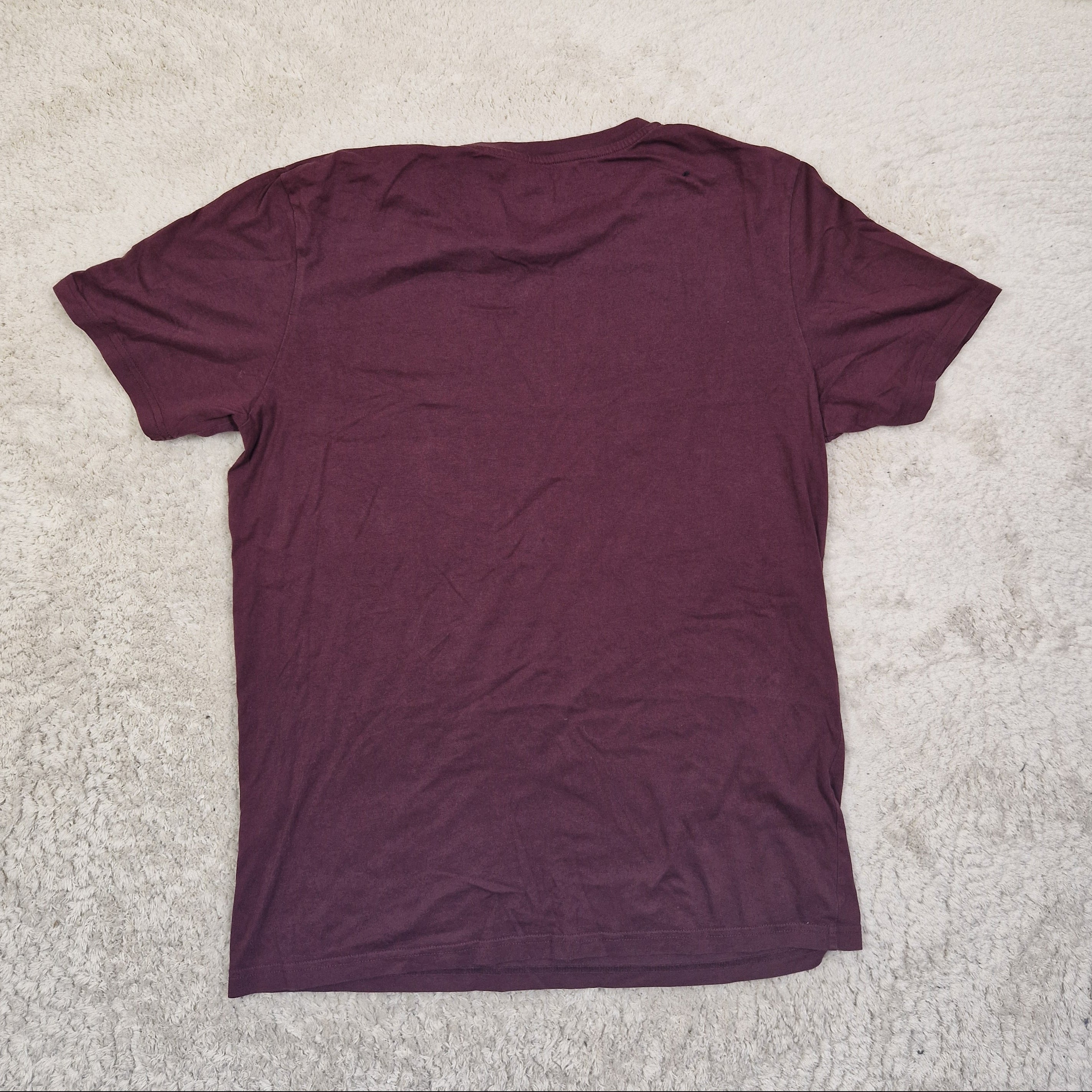 Maroon t-shirt on a beige carpet