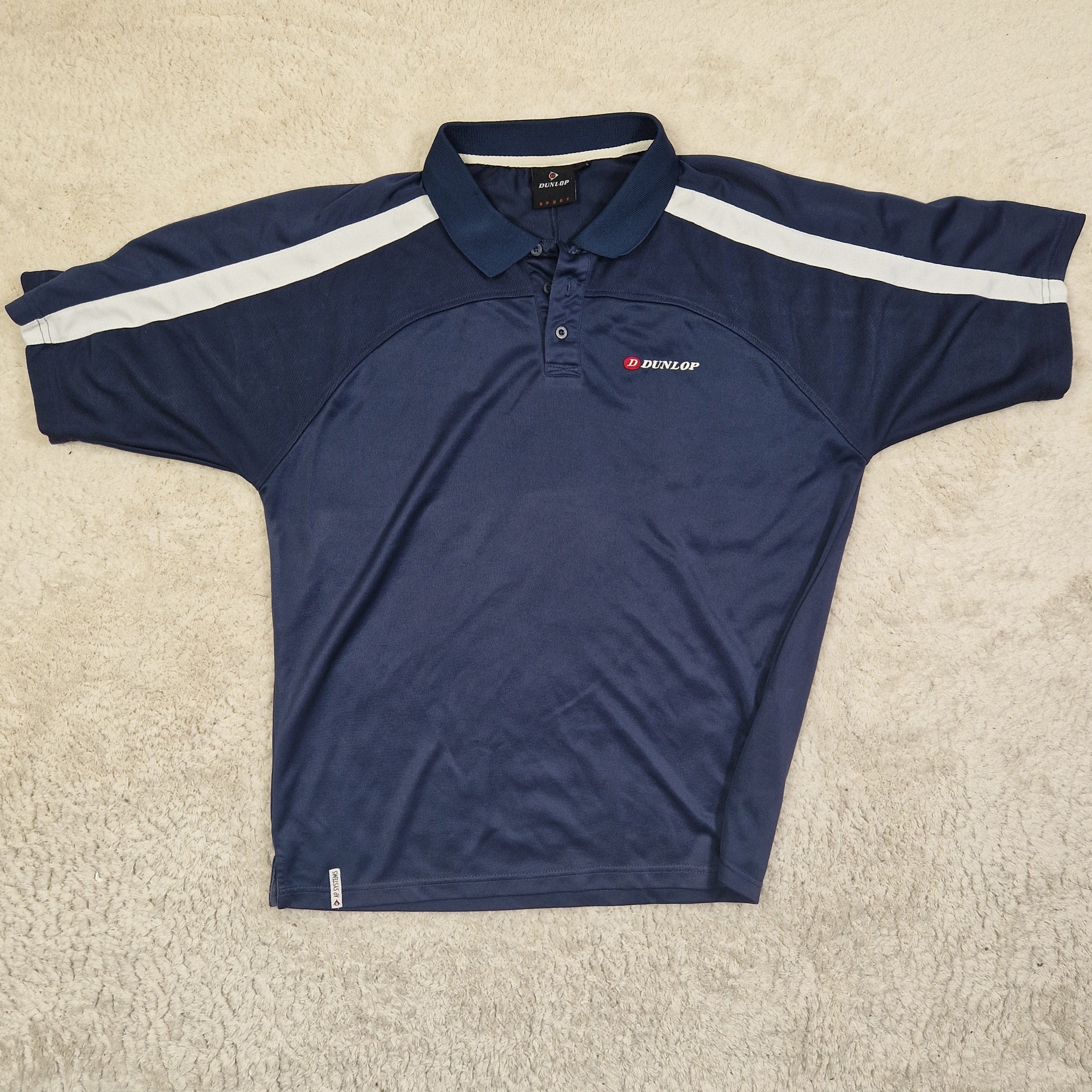 Navy blue athletic shirt with white stripes on a beige carpet