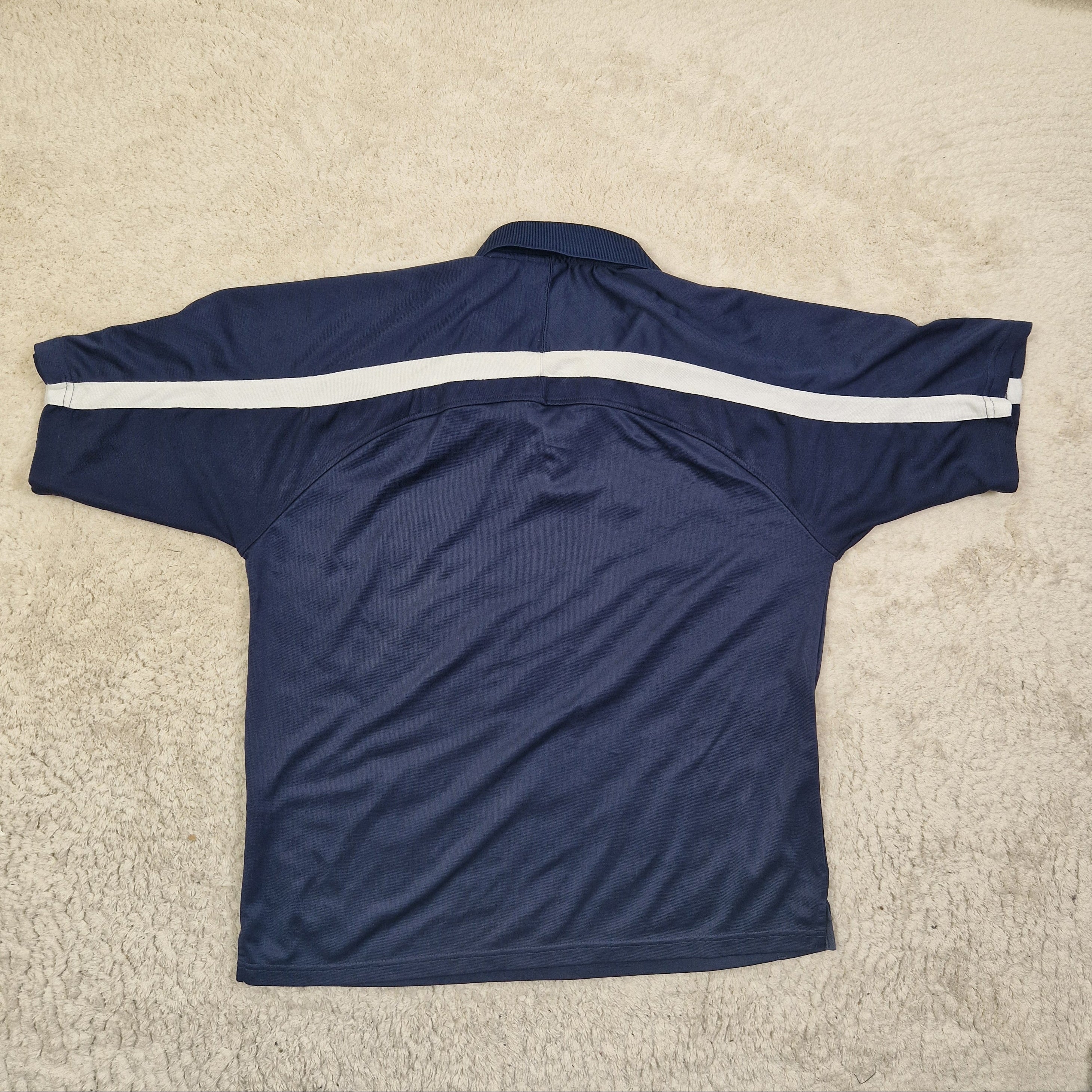 Navy blue athletic top with a white zipper on a beige carpet