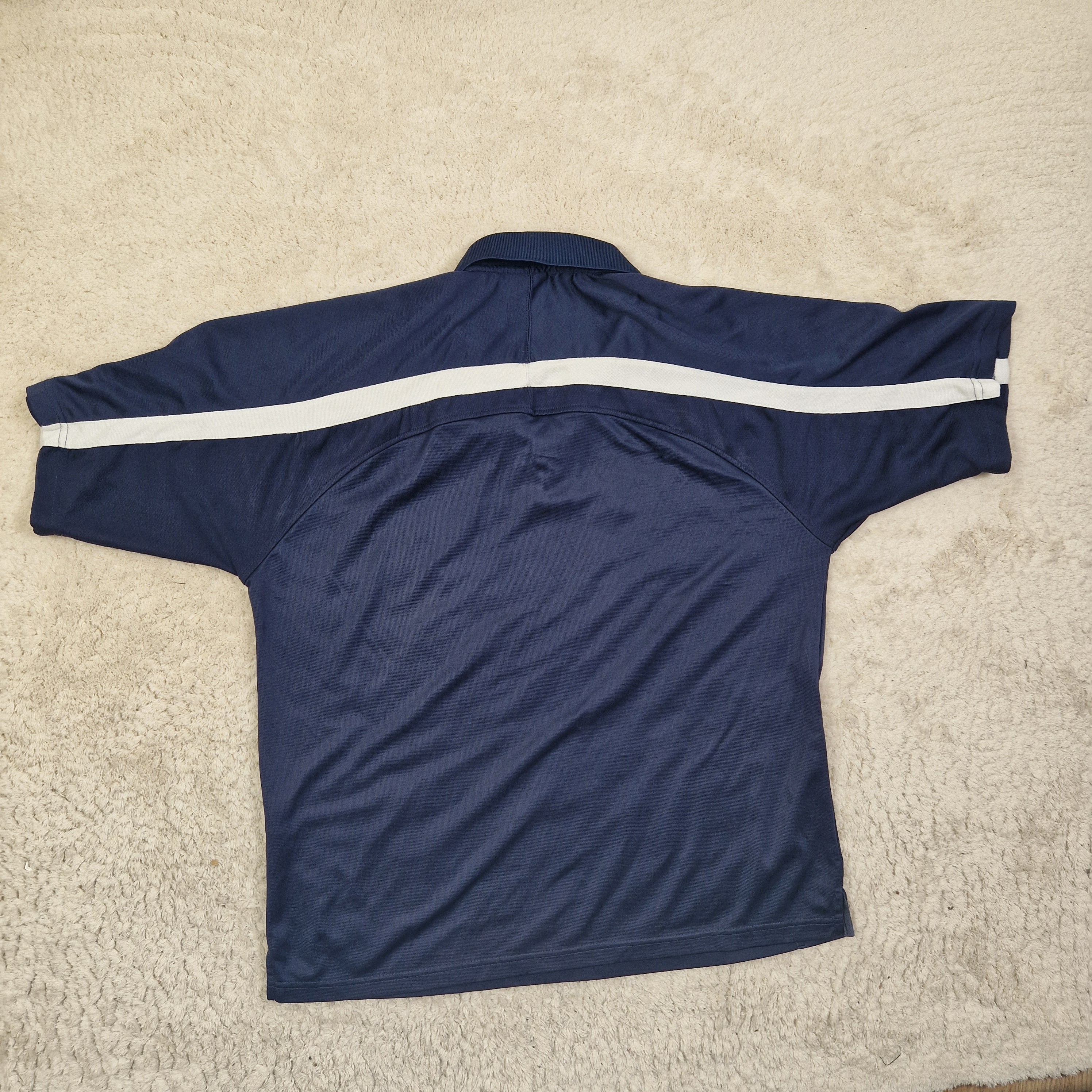 Blue athletic top with a white stripe on a beige carpet