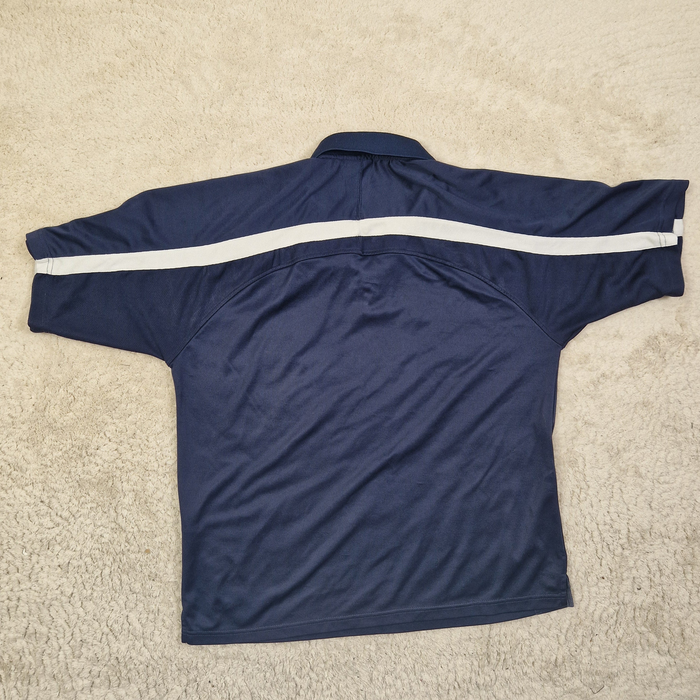 Navy blue long-sleeve shirt with a white stripe on a beige carpet