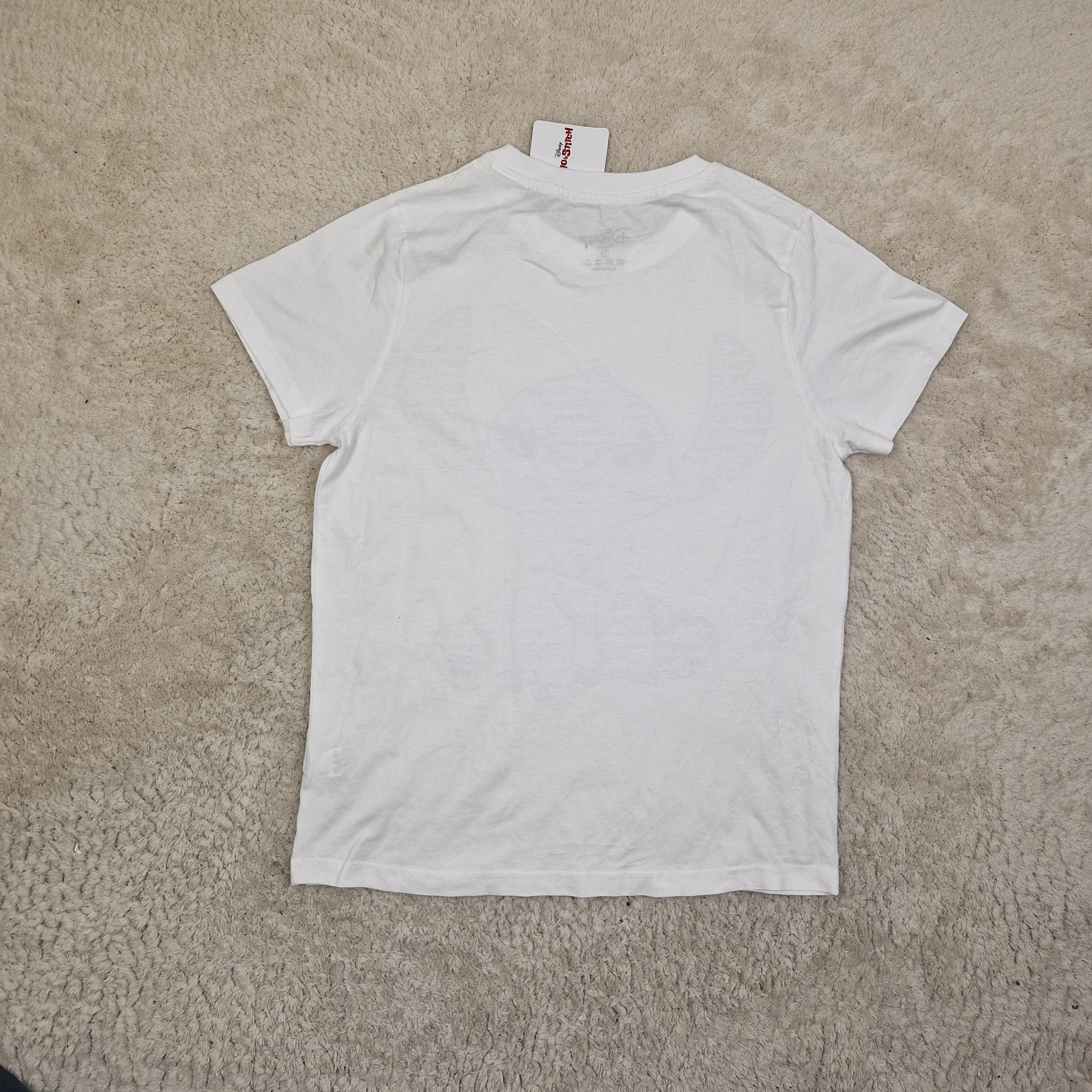 White t-shirt with a brand label on a beige carpet