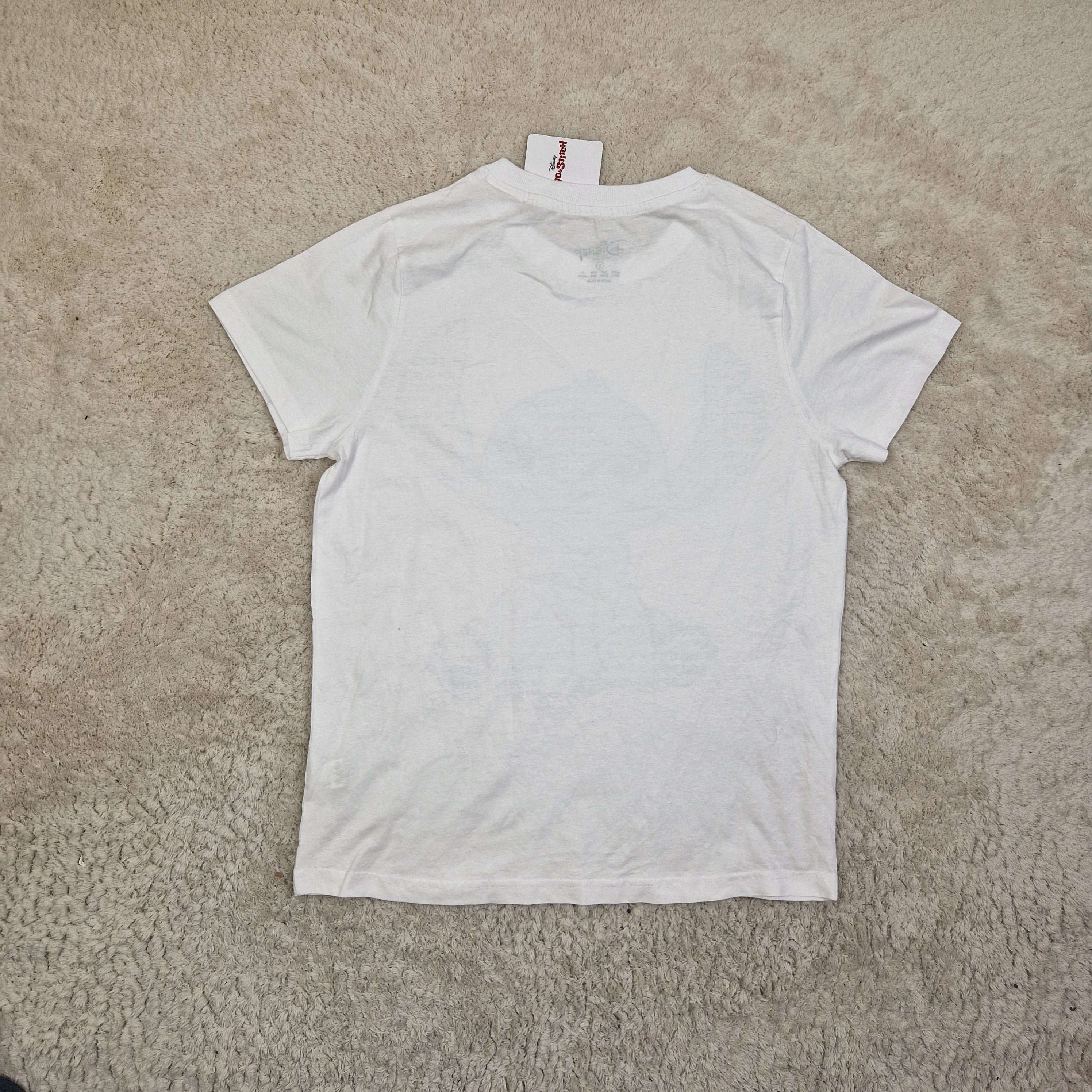 White t-shirt with a brand tag on a beige carpet
