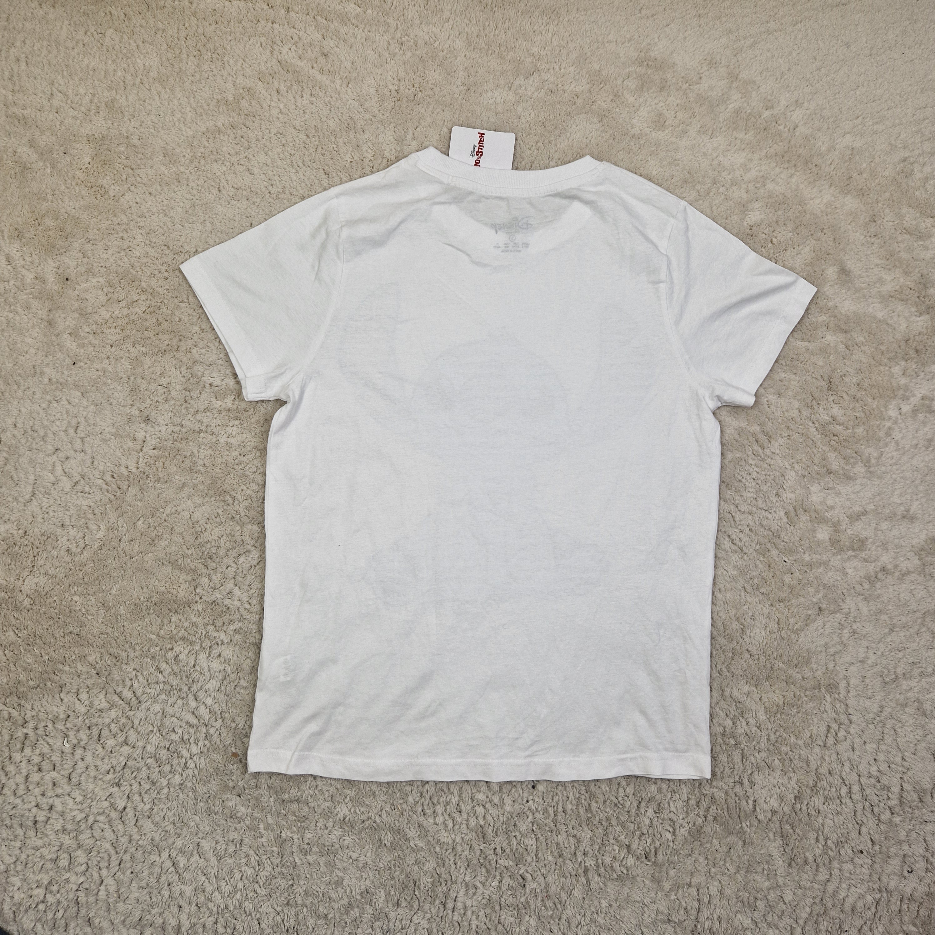 White t-shirt with a brand tag on a beige carpet