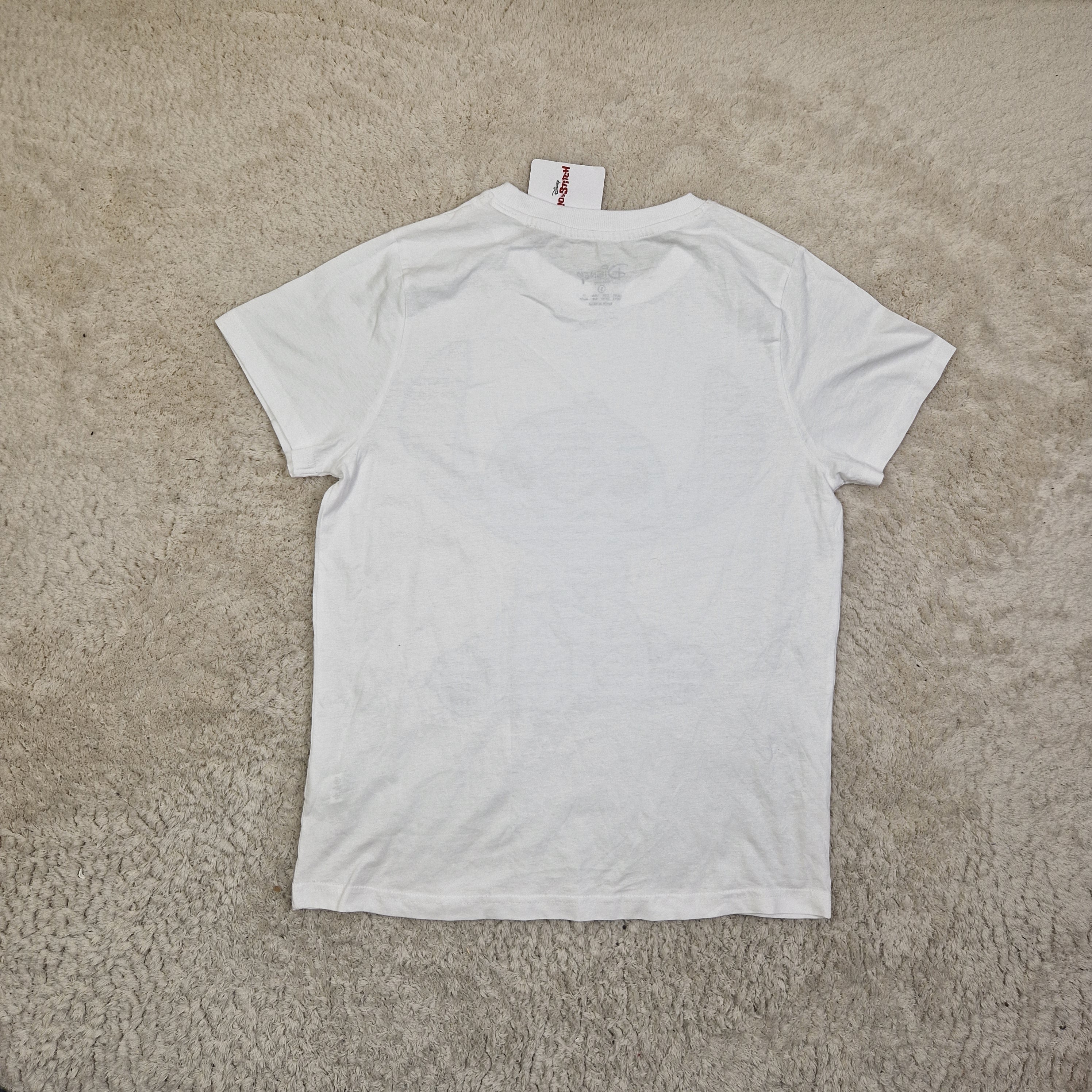 White t-shirt with a brand tag on a beige carpet