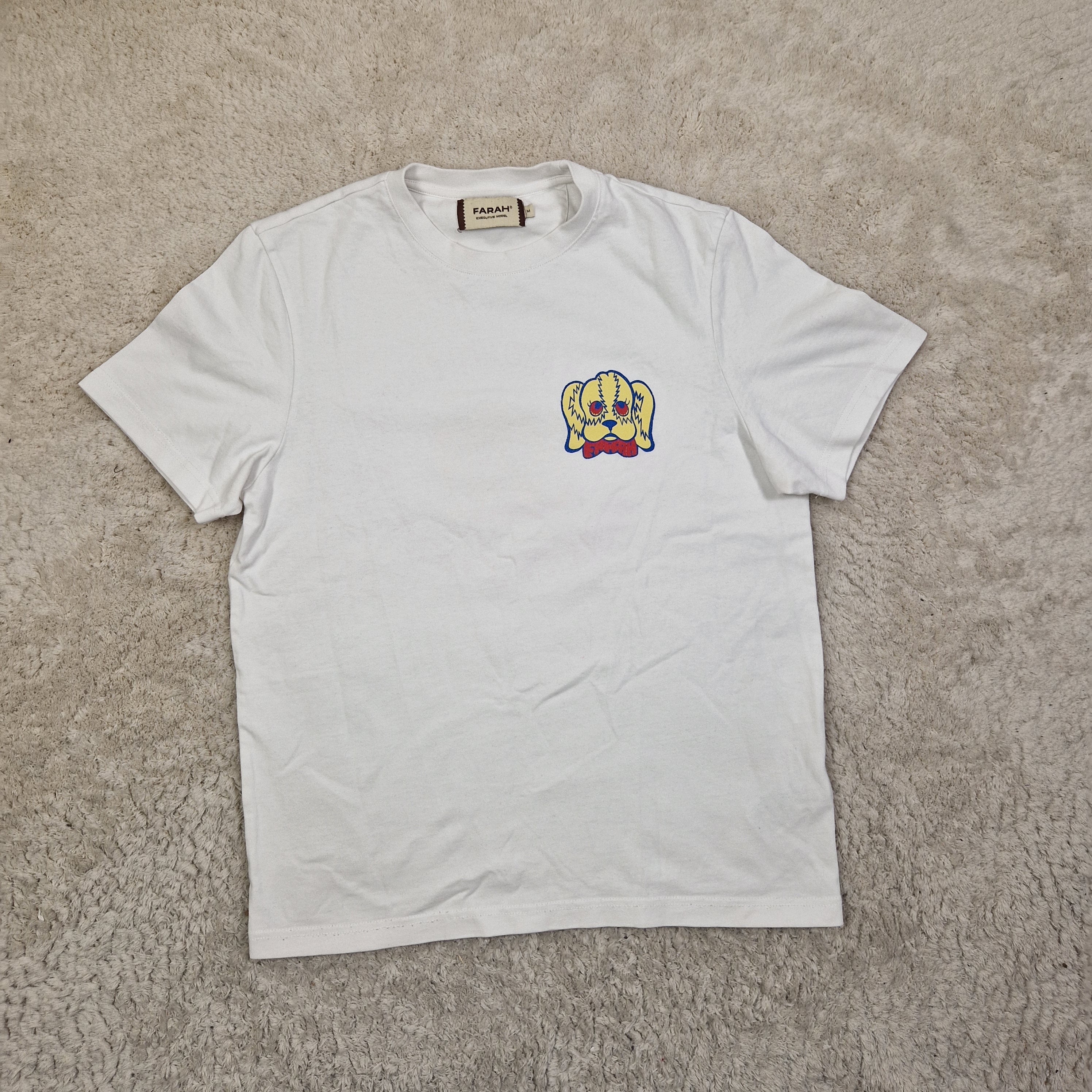 White t-shirt with a colorful logo on a beige carpet