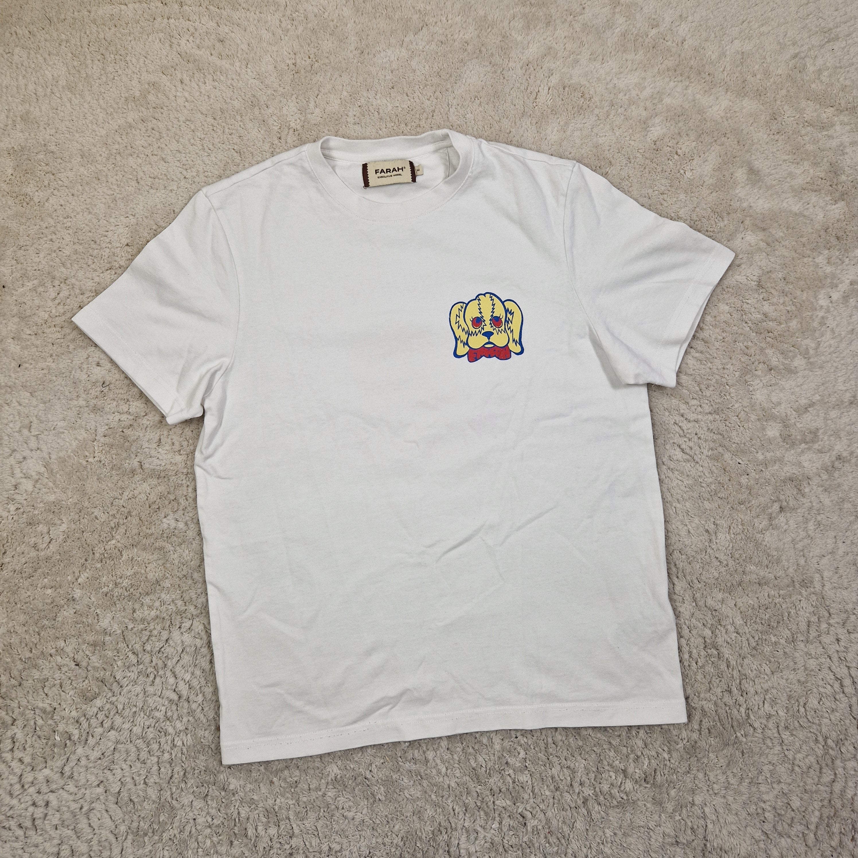 White t-shirt with a colorful graphic on a beige carpet