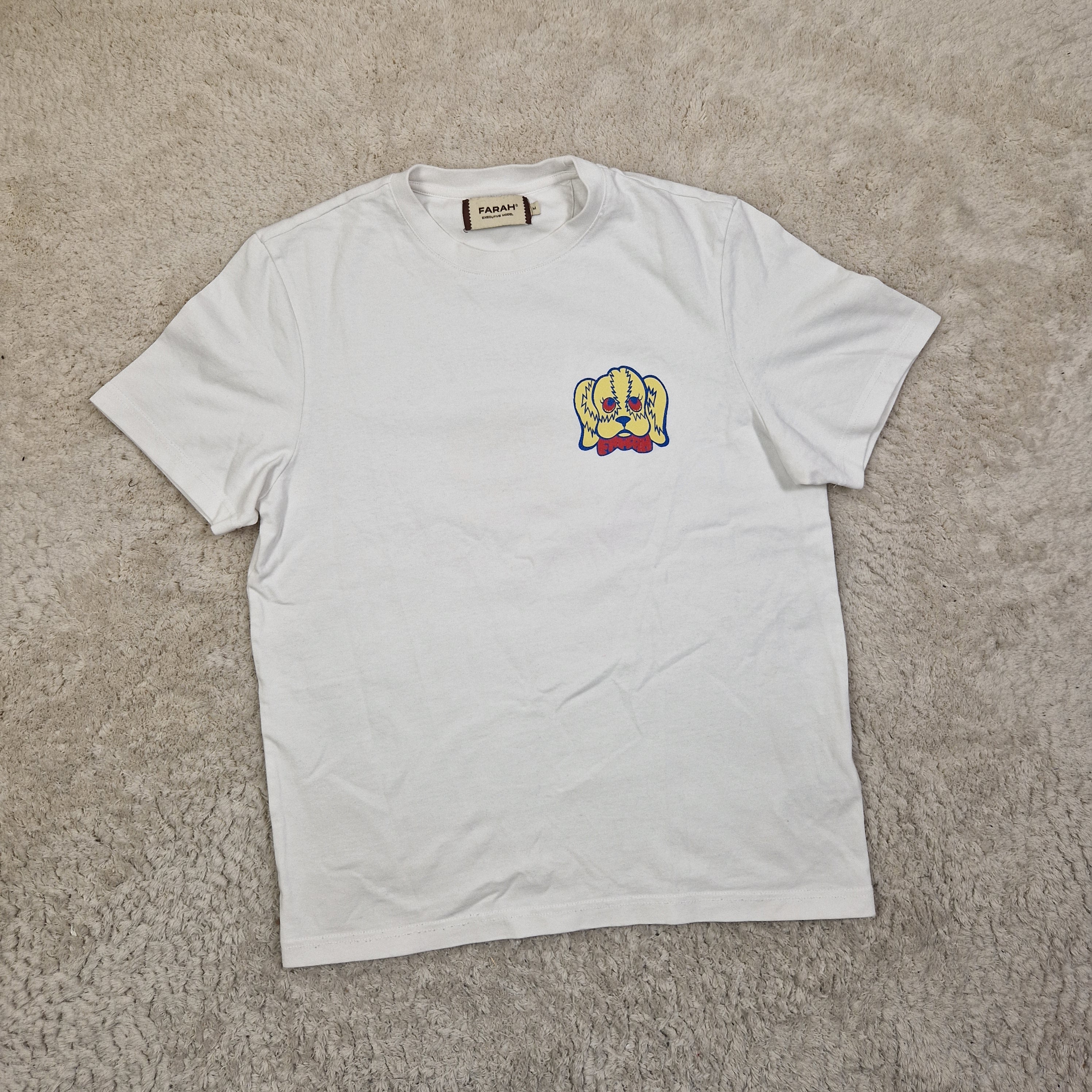 White t-shirt with a colorful logo on a beige carpet