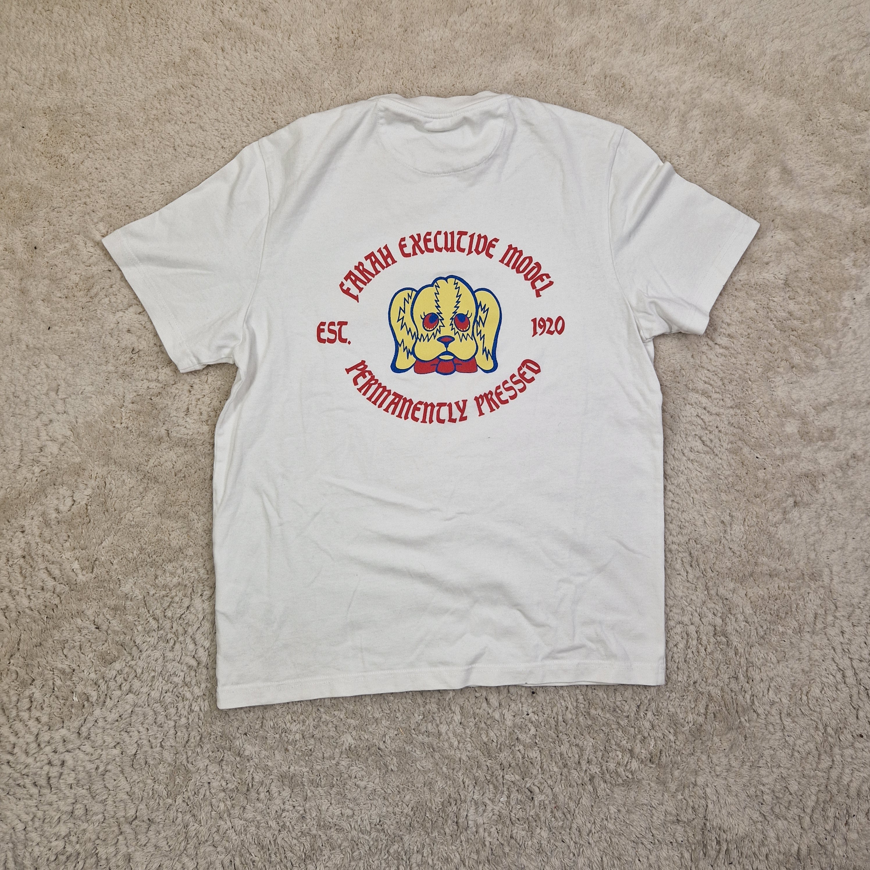 White t-shirt with a logo and text on a beige carpet