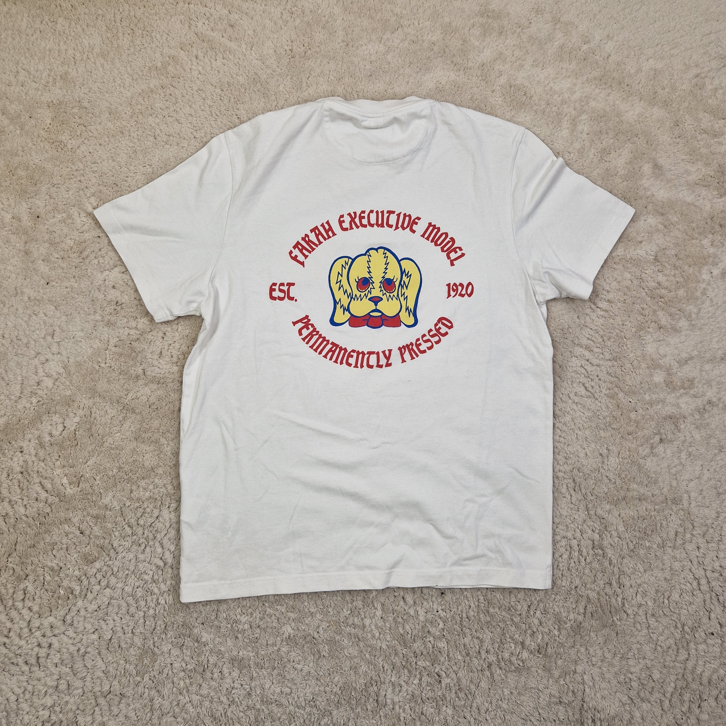 White t-shirt with a logo and text on a beige carpet
