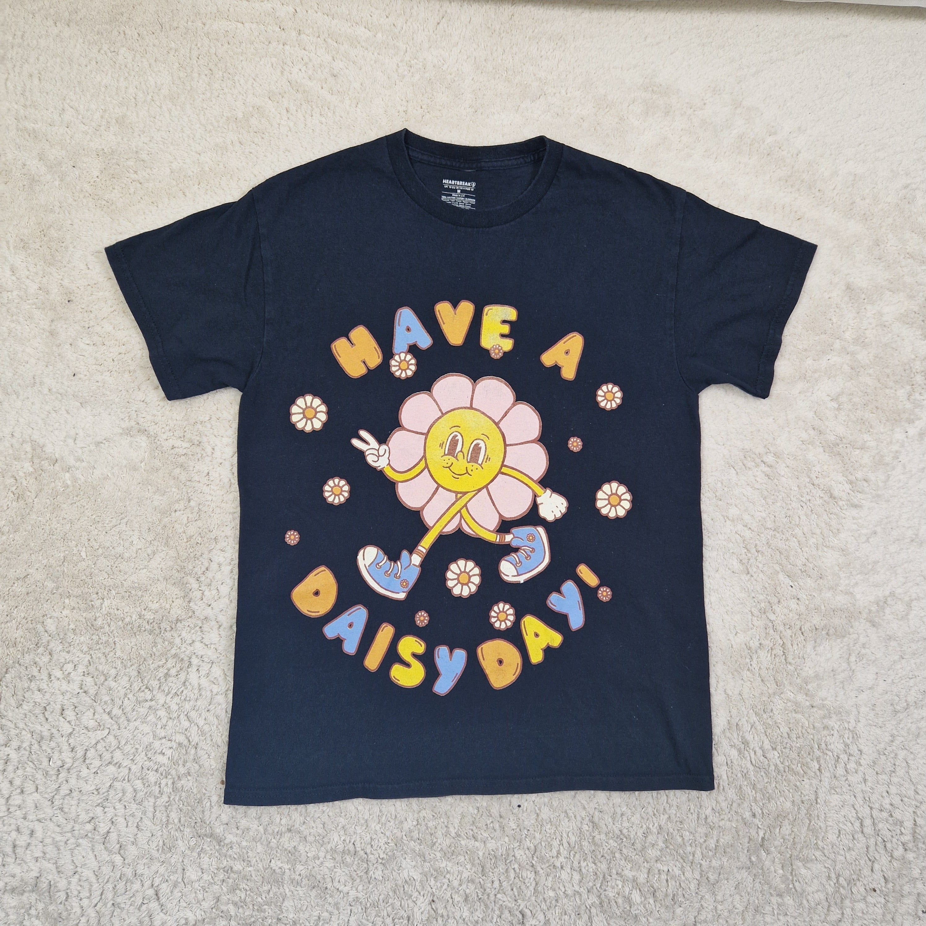 Navy blue sweatshirt with colorful graphic design on a beige carpet