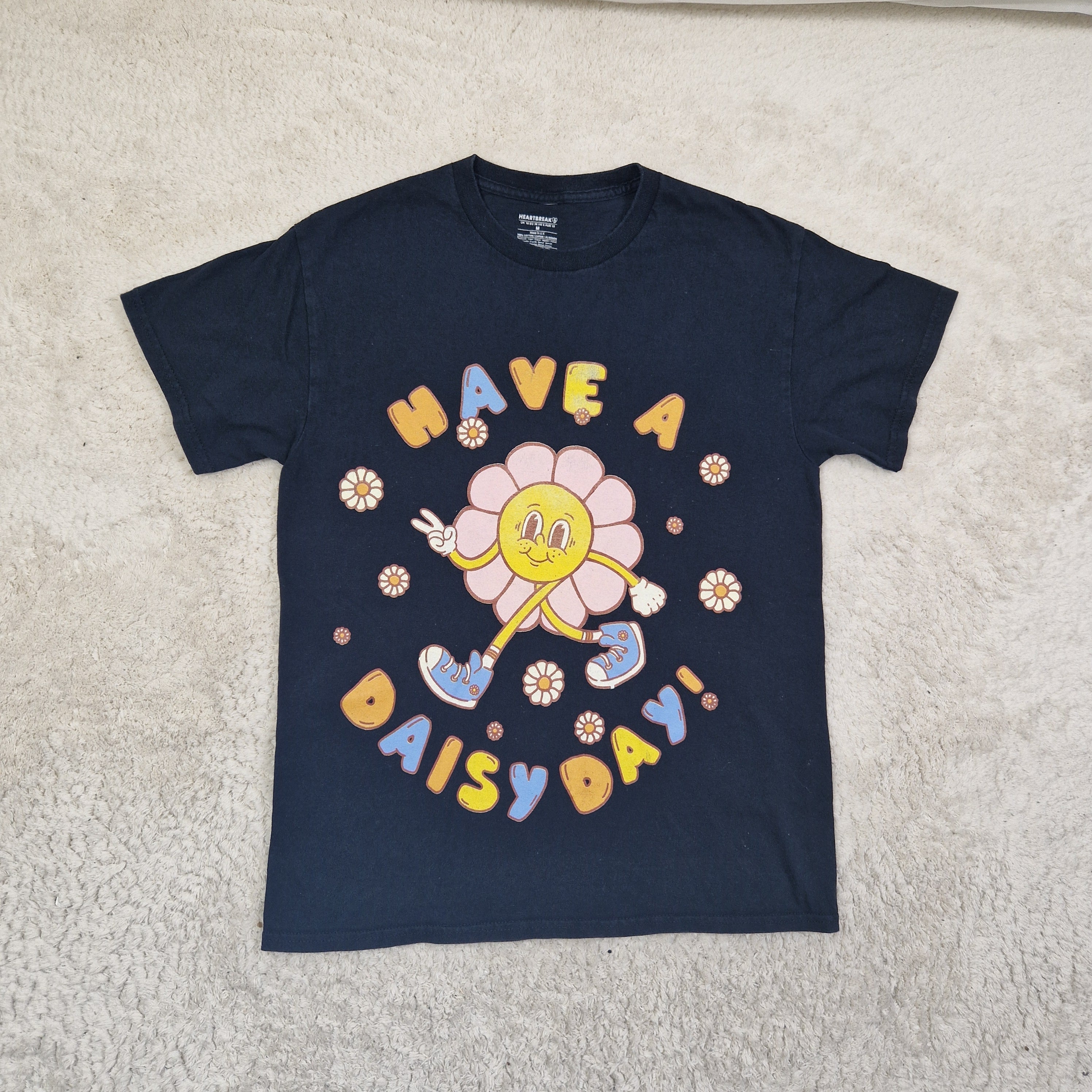 Navy blue t-shirt with colorful graphic design on a beige carpet