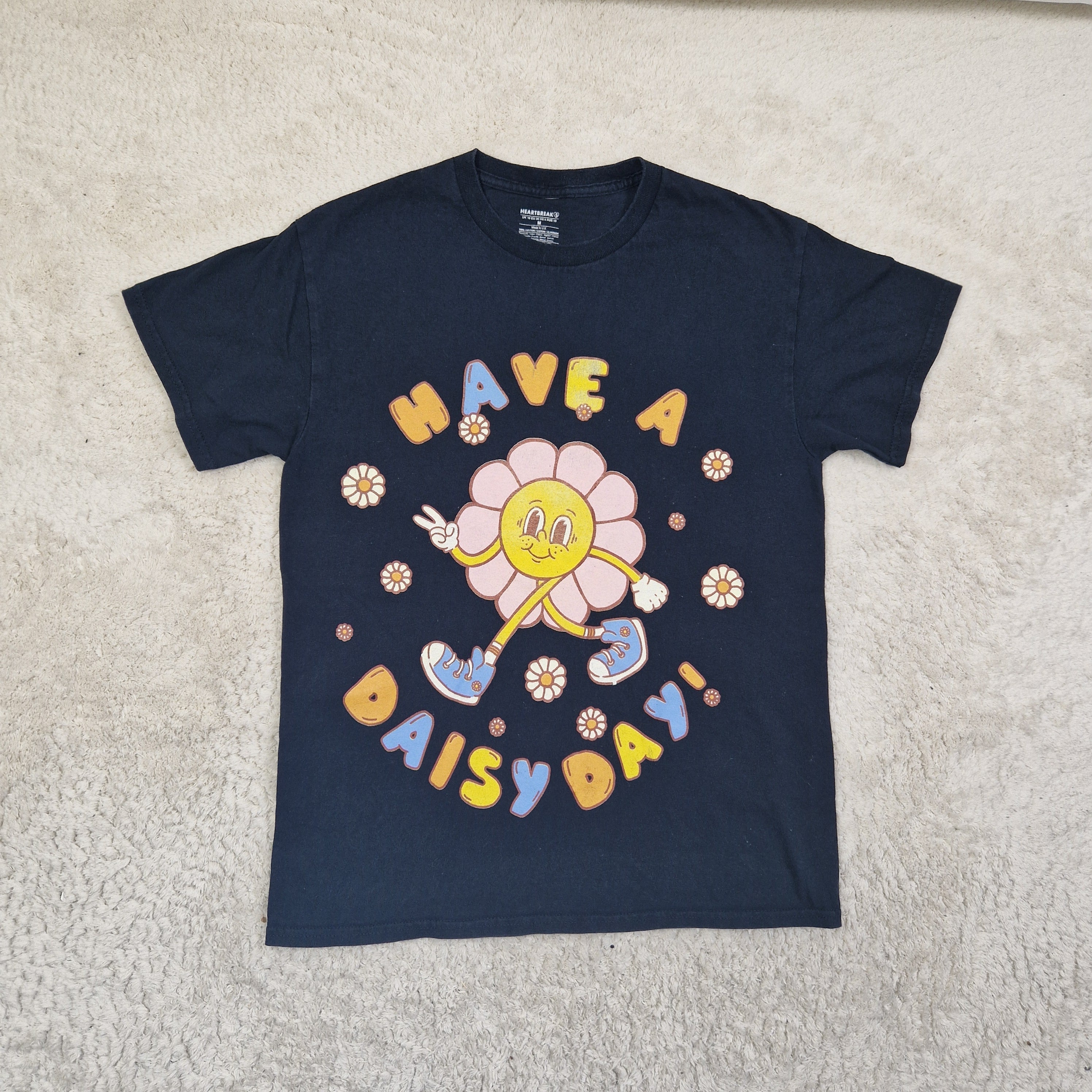 Navy blue long-sleeve shirt with colorful graphic design on a beige carpet