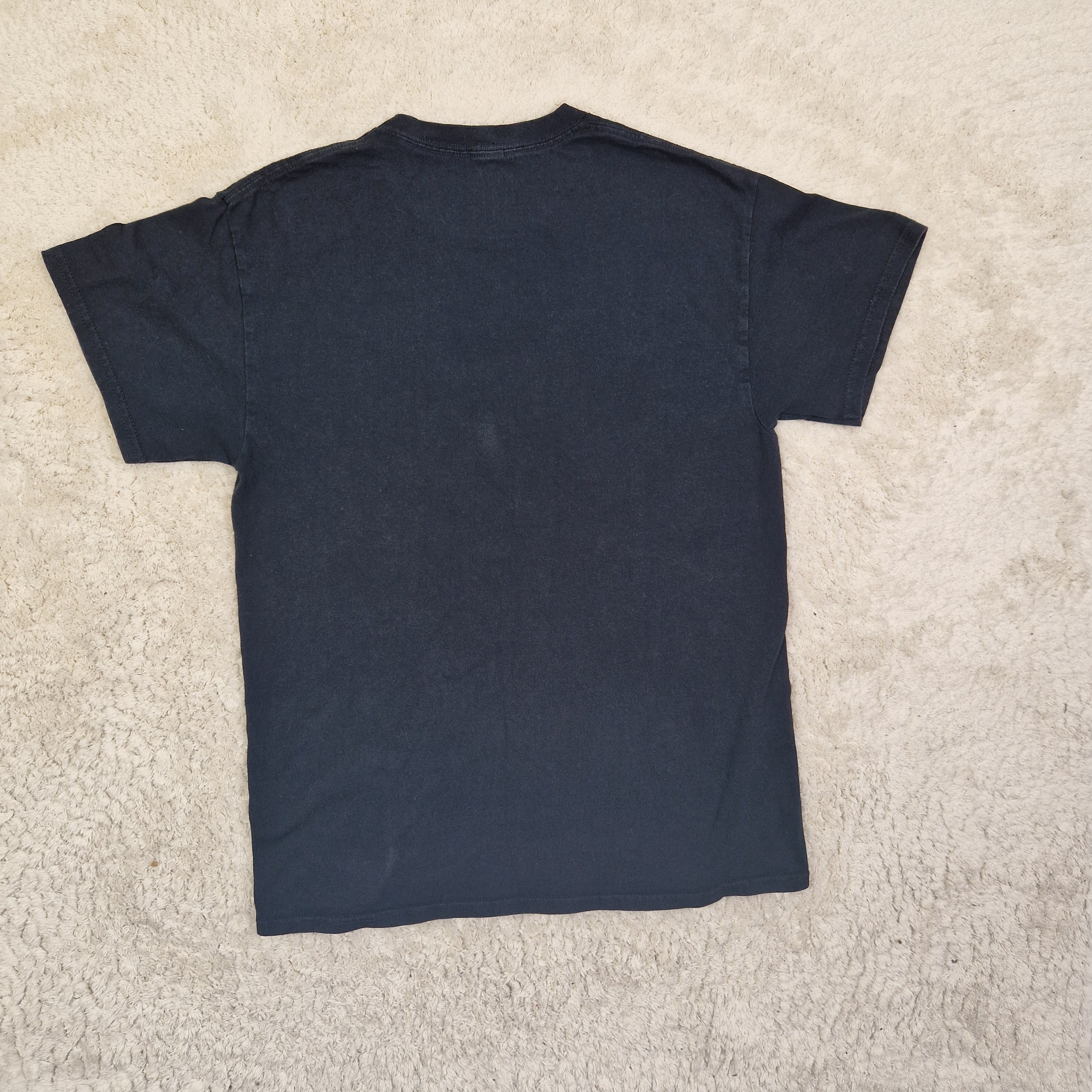 Folded navy blue t-shirt on a beige carpet