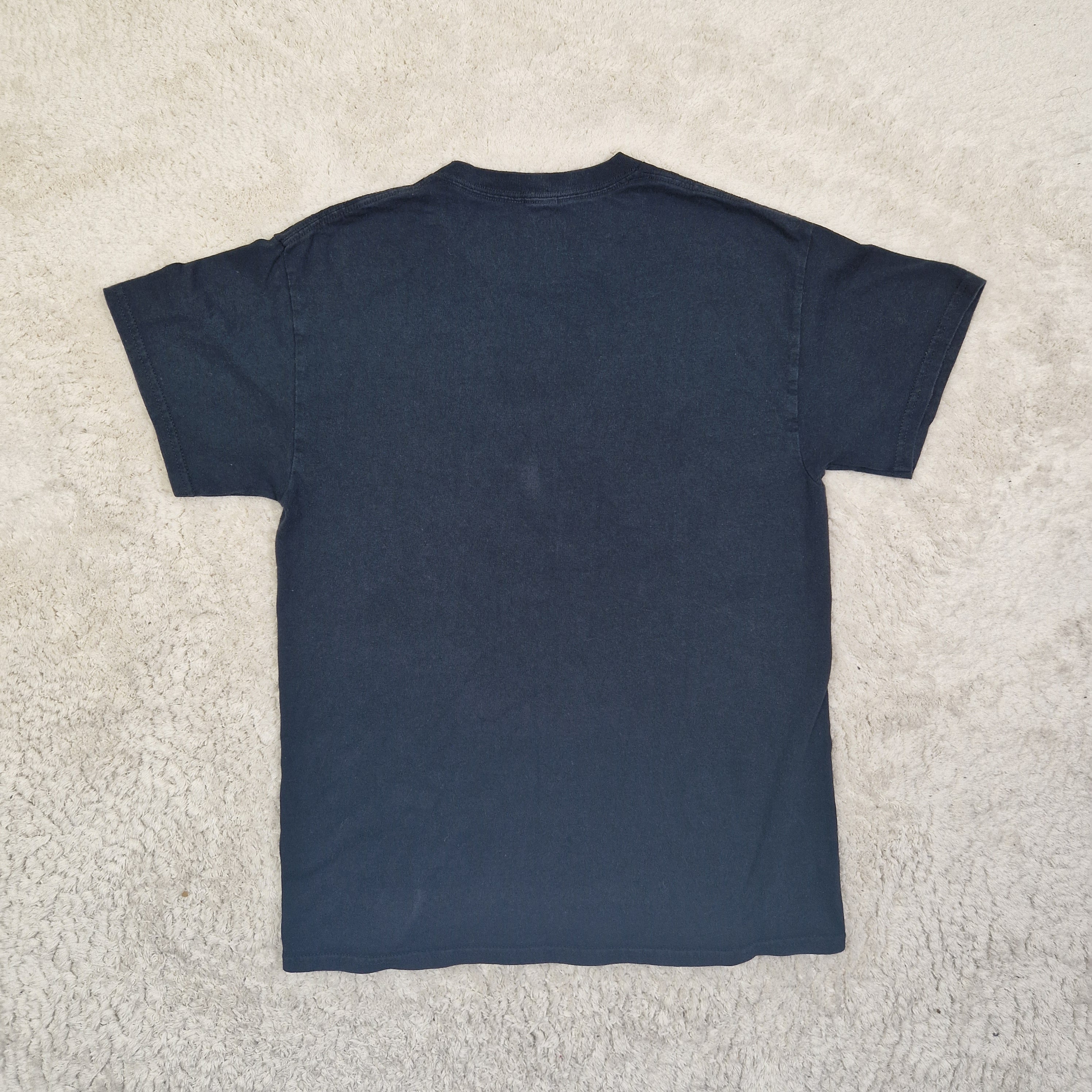 Folded navy blue t-shirt on a beige carpet