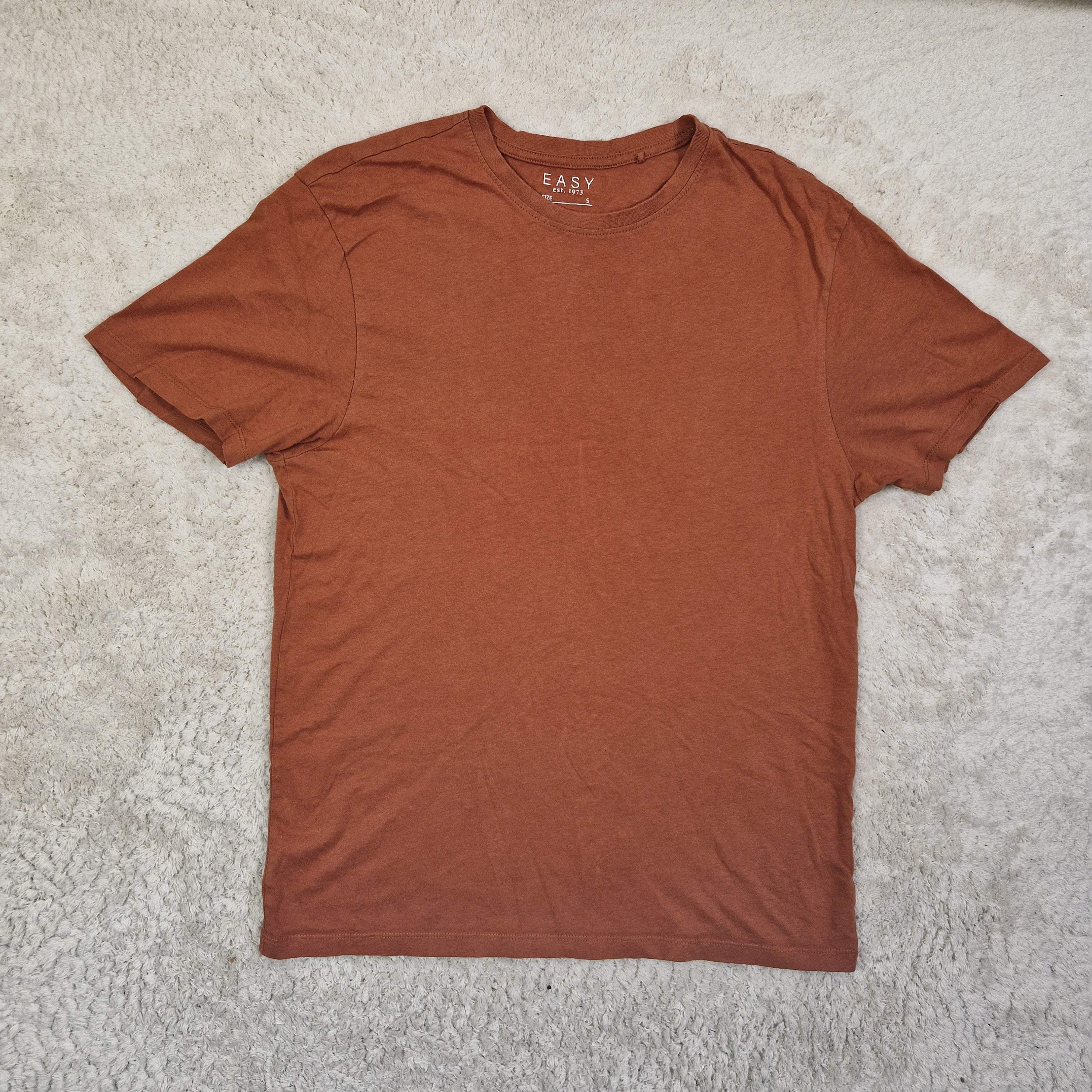 Brown t-shirt on a light gray carpet