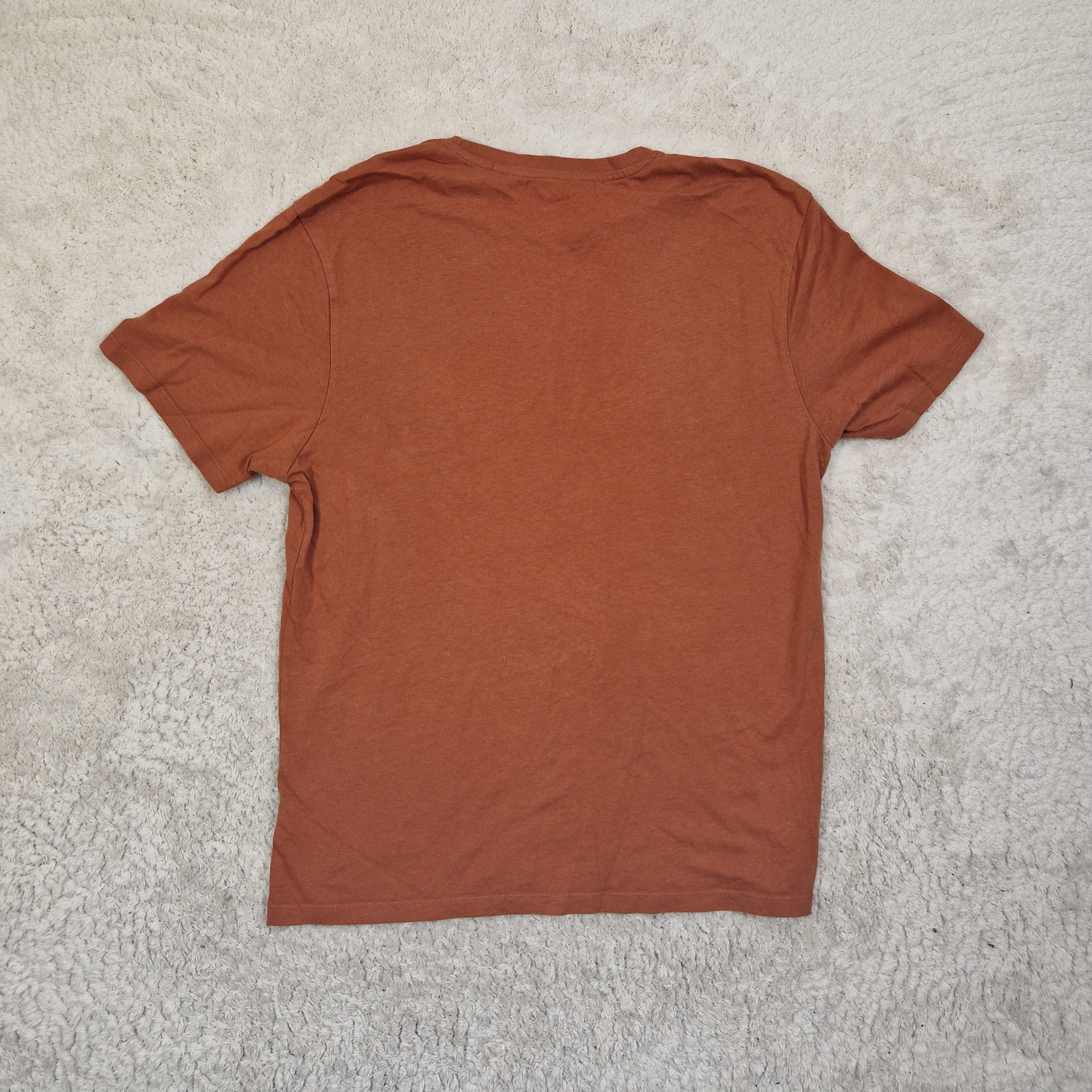 Brown t-shirt on a textured beige surface
