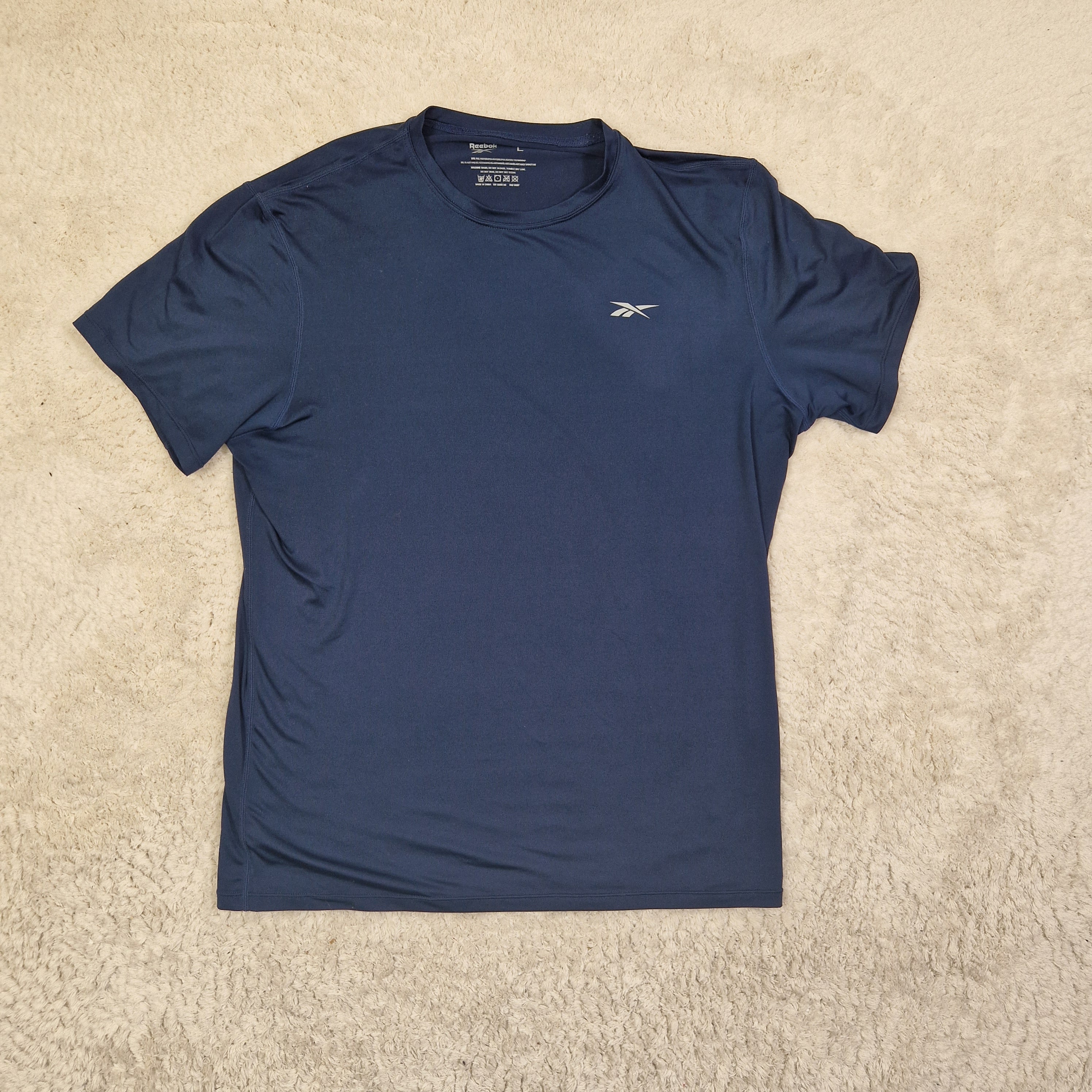 Blue t-shirt with a logo on a beige carpet